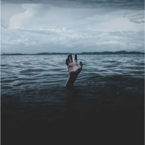 Hand reaching out of a large lake. The hand represents someone seeking help.