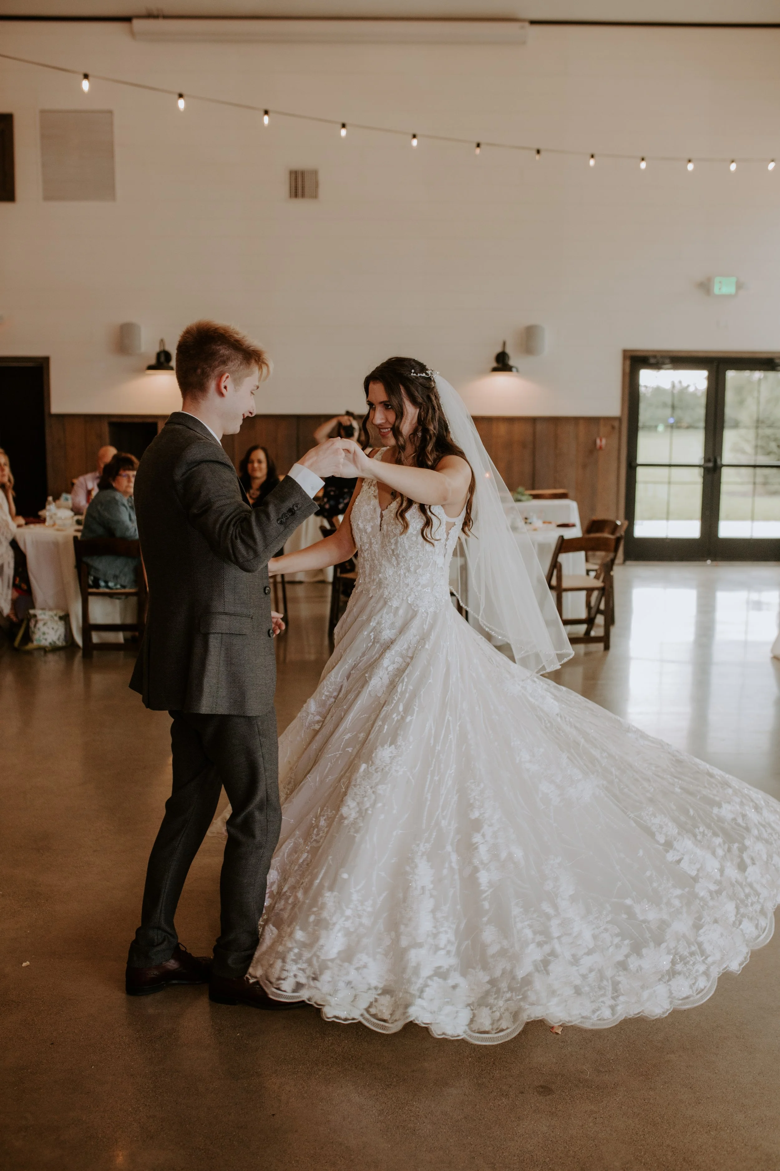 Bride and groom share their first dance at the reception, with the bride's dress flowing beautifully as they move.