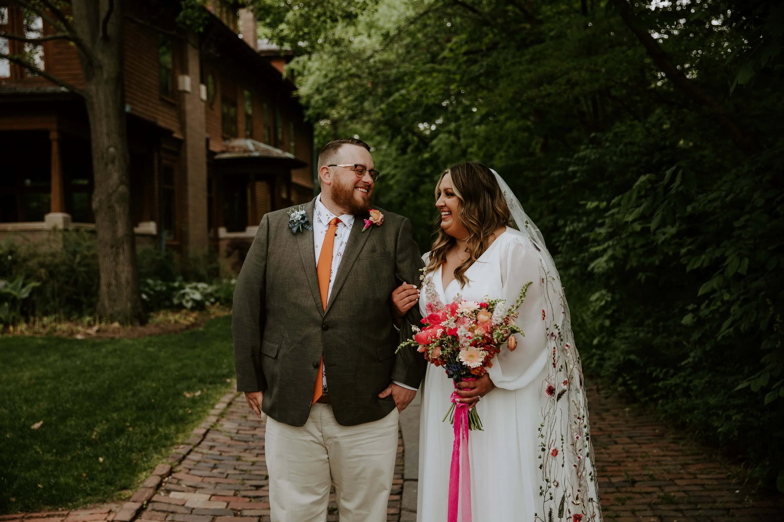 The bride and groom look at each other smiling while standing near the Oakhurst House.