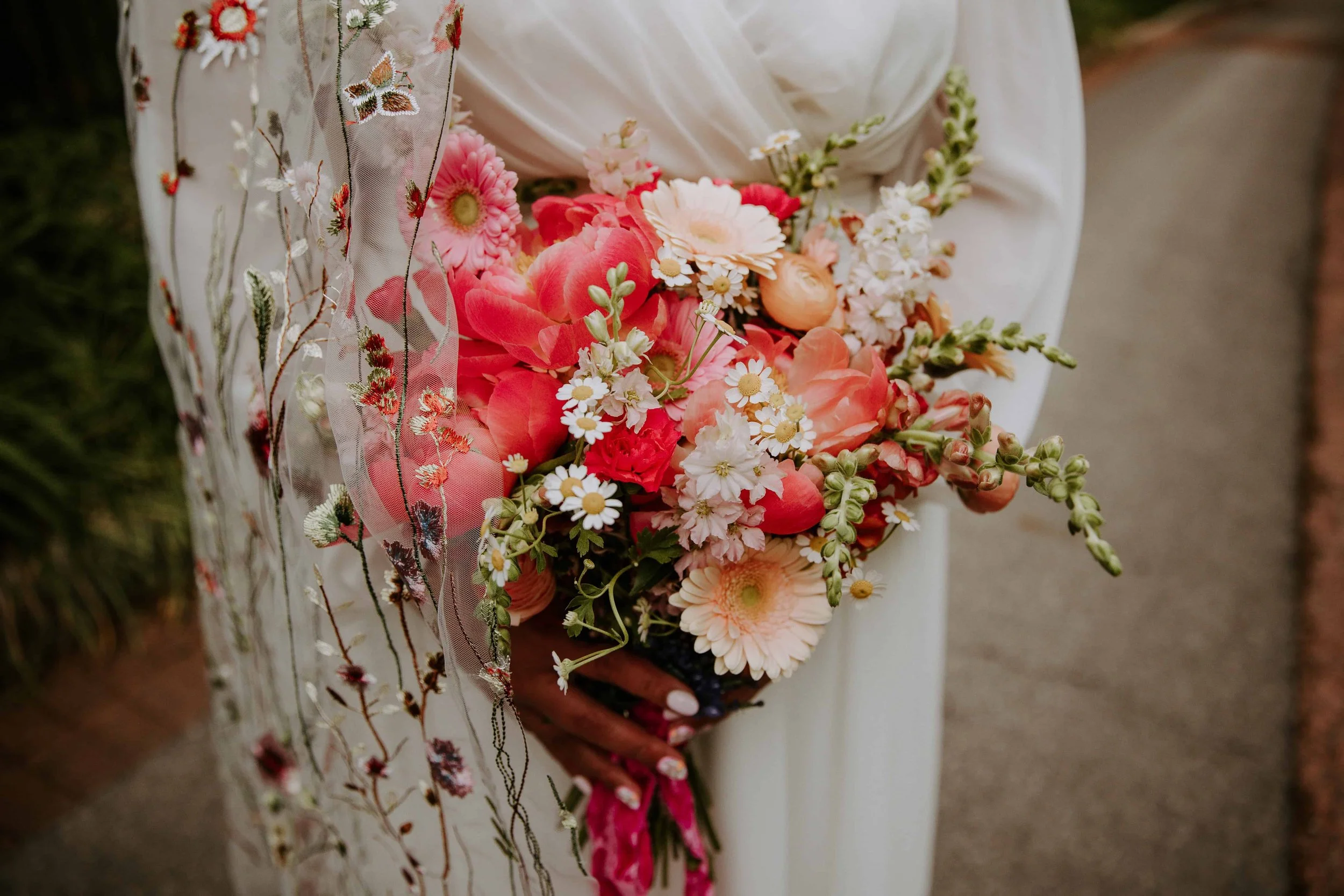 Close up of the bride holding her bouquet with a floral veil.