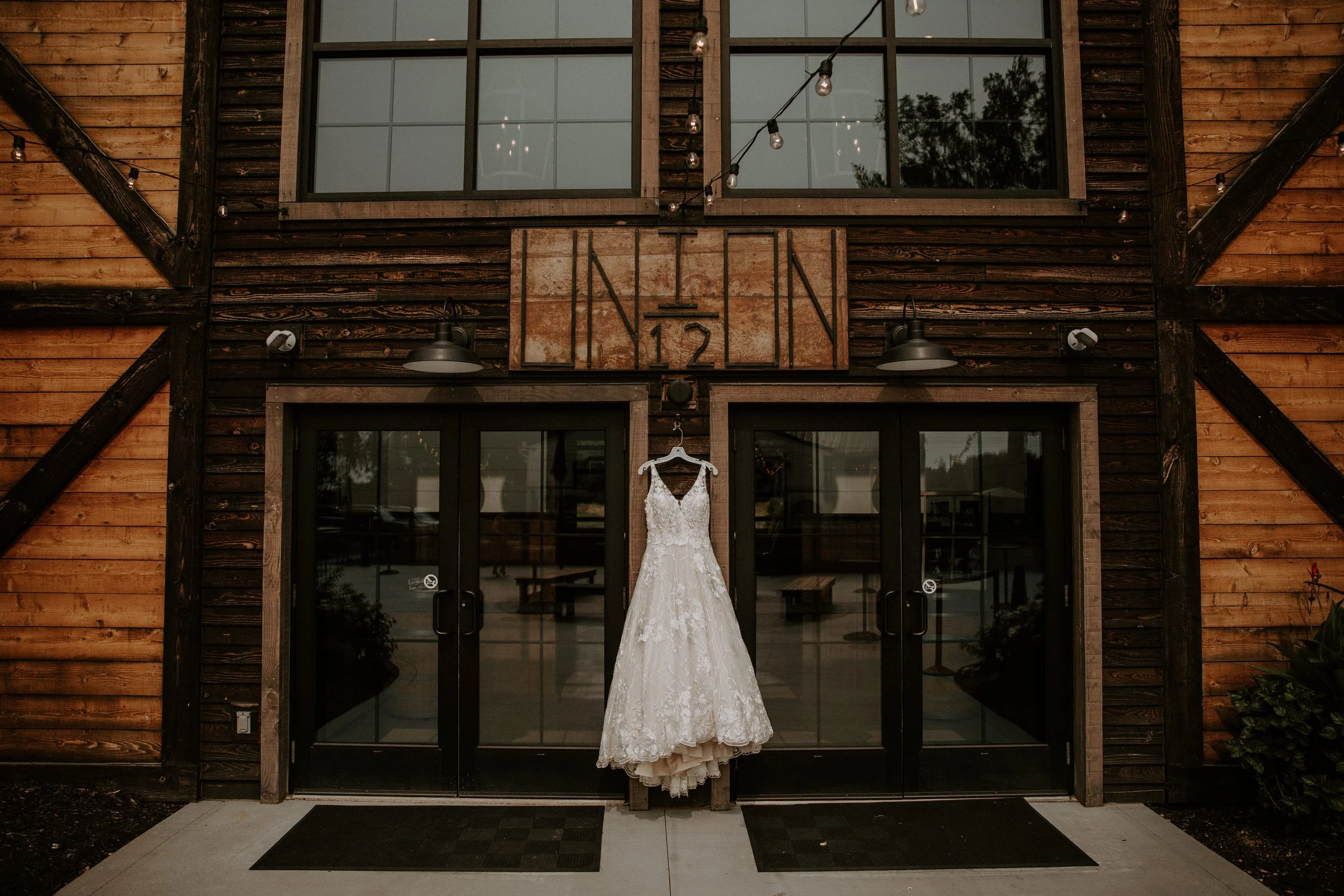 A wedding dress hanging on the door of the Union 12 venue in Fort Wayne, Indiana, with rustic wooden details in the background.