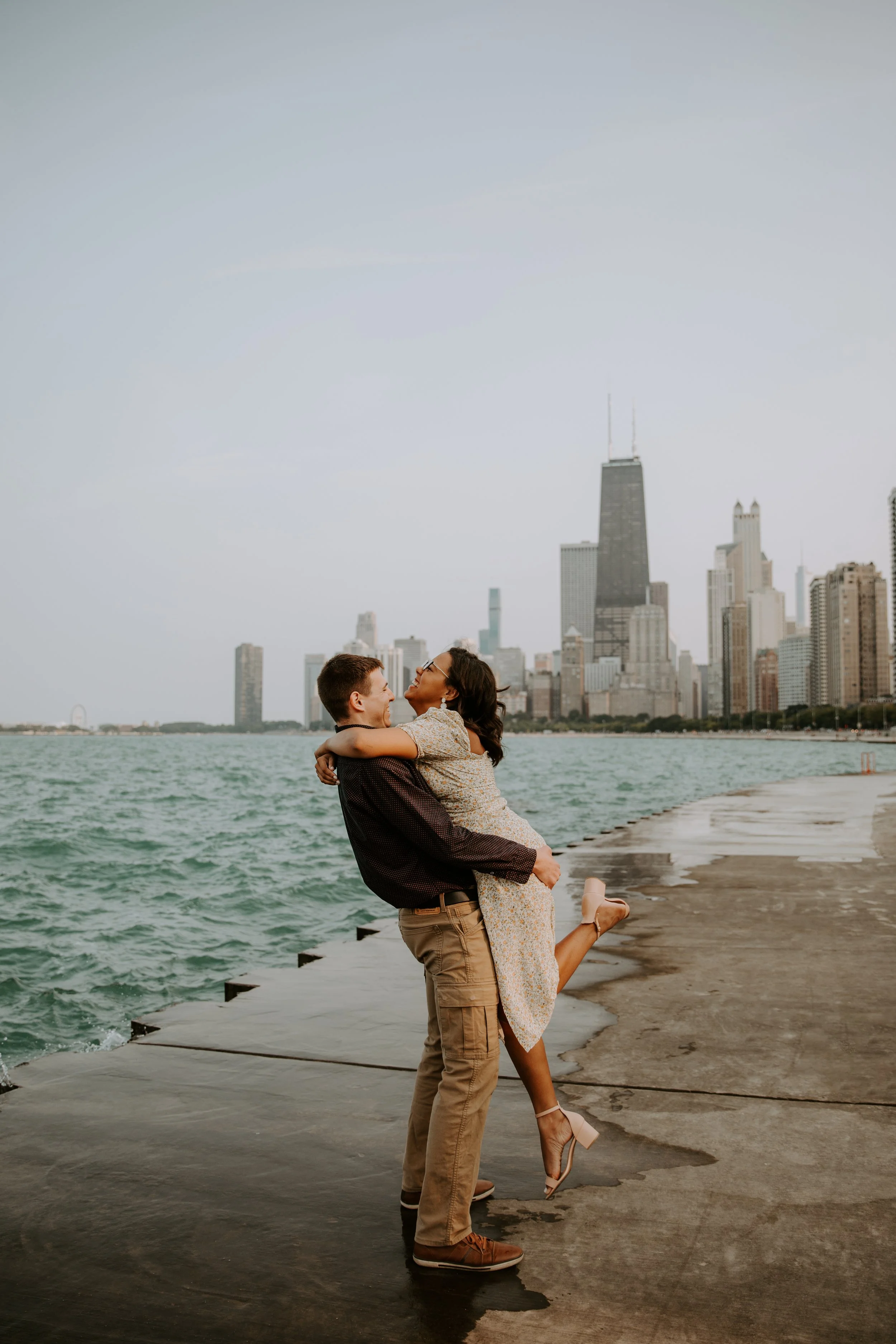 Groom-to-be lifting his fiancée as they embrace by the lake.