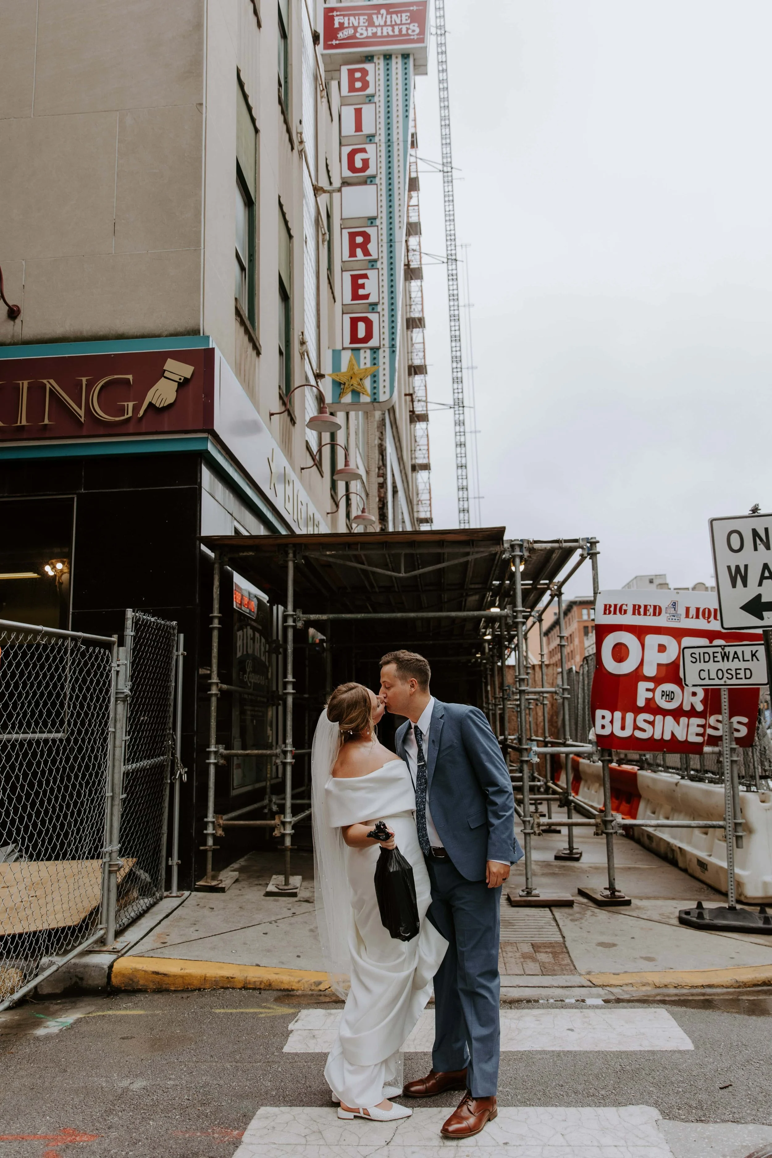 The bride and groom kiss in front of the Big Red Liquors in Indianapolis.