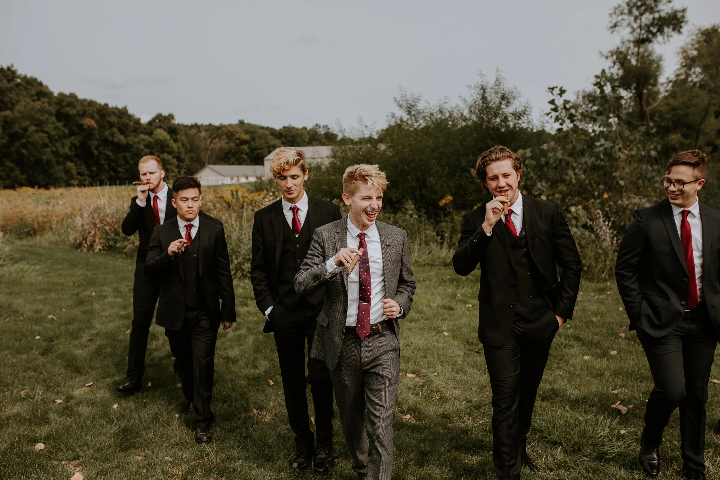 Groom and groomsmen walking together, each with a cigar, sharing a lighthearted moment before the ceremony.