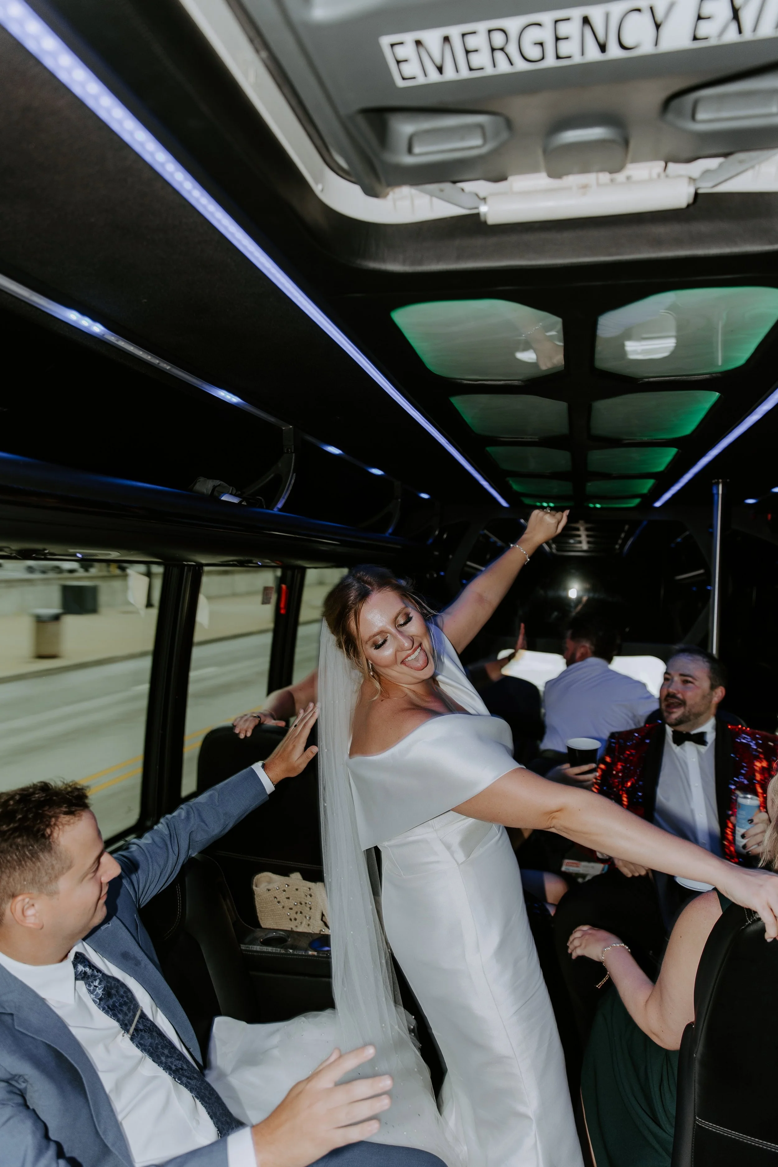 The bride dances on a party bus surrounded by her husband and friends.