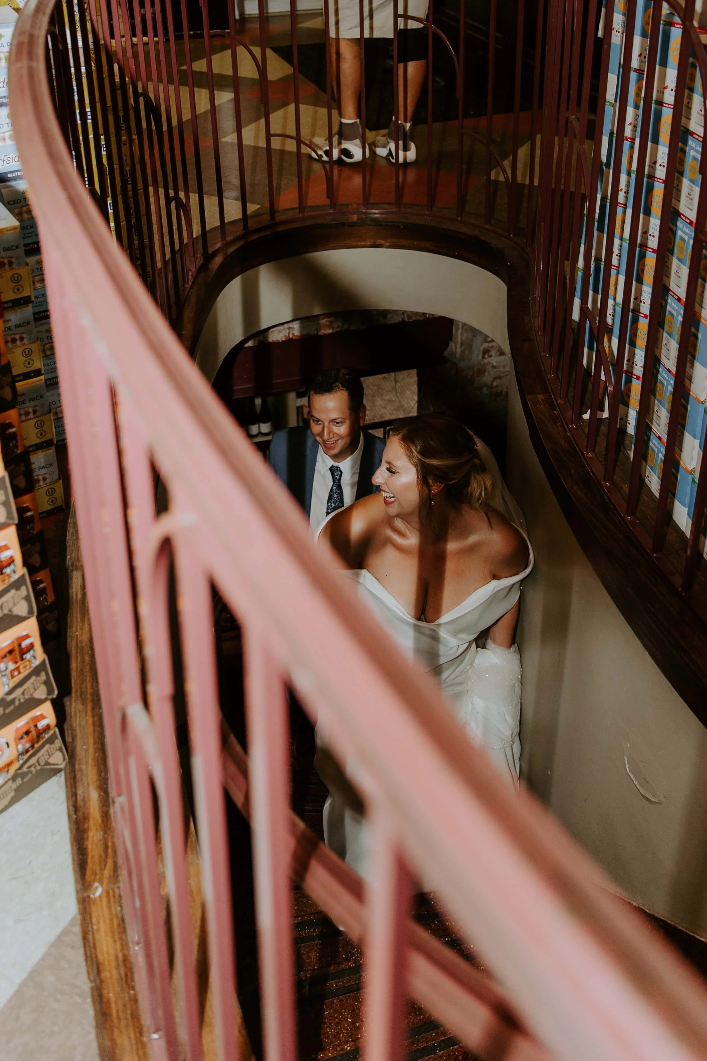 The bride and groom walk up the stairs from the basement of the liquor store.