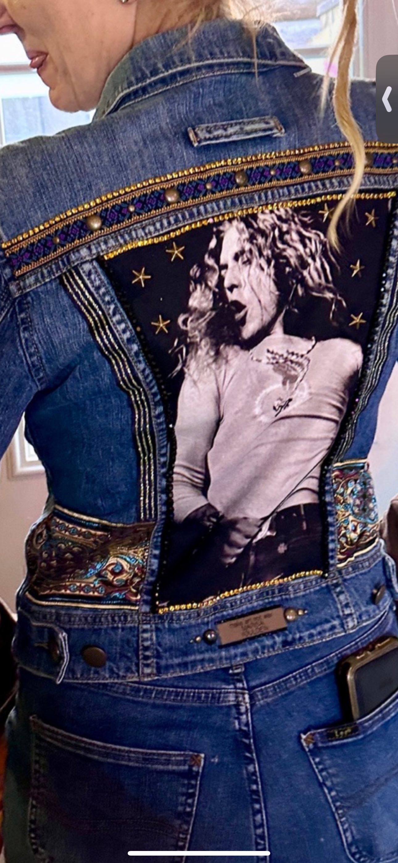 Person wearing a decorated denim jacket with a black-and-white image and stars.