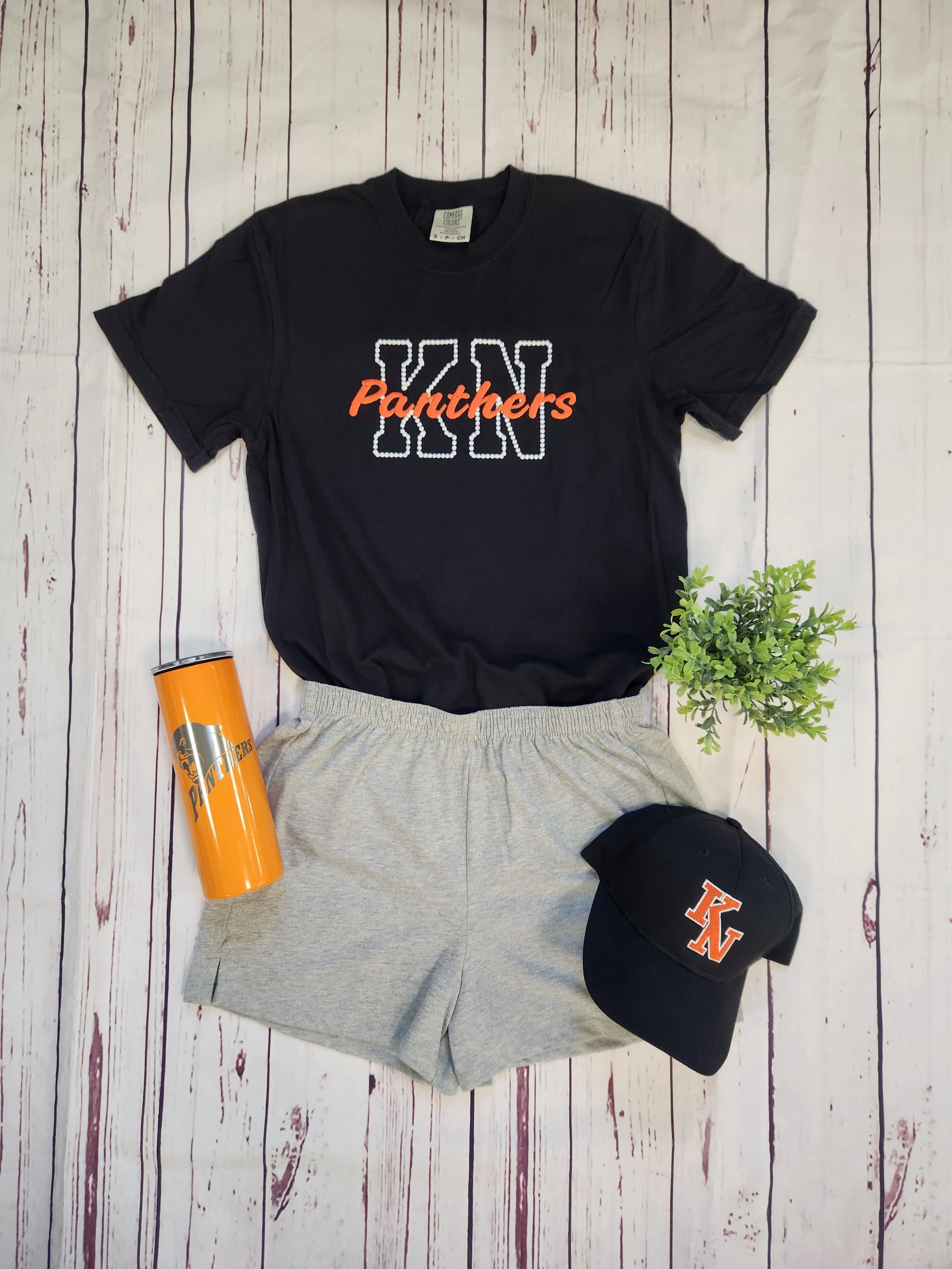 Embroidered KN Panthers Comfort Color T-Shirt, black t-shirt with letters K and N embroidered in white thread with Panthers embroidered on top of the letters in orange thread, Knob Noster Panthers