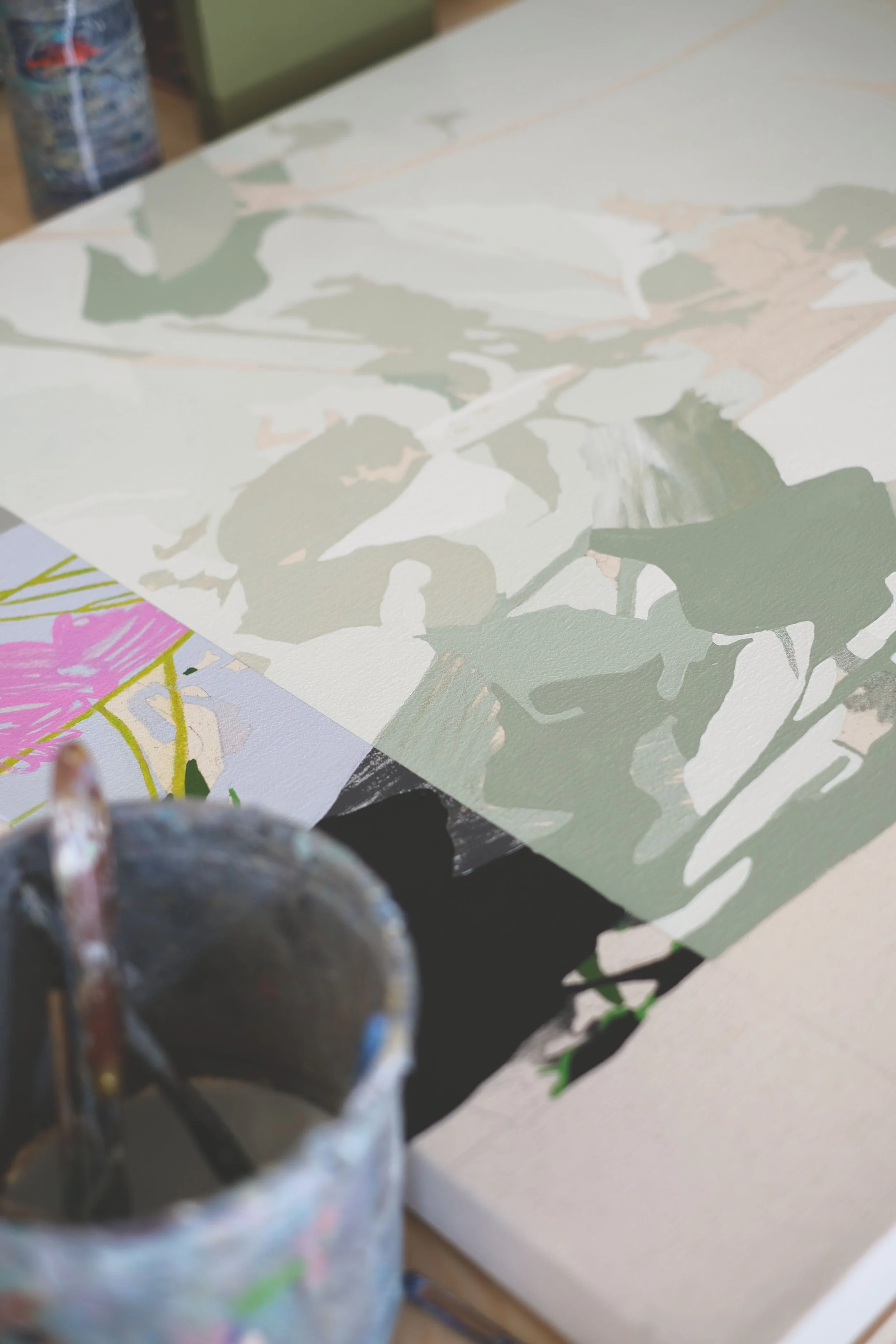 Close-up of an artist's palette and a partially painted canvas with leaf and floral patterns.