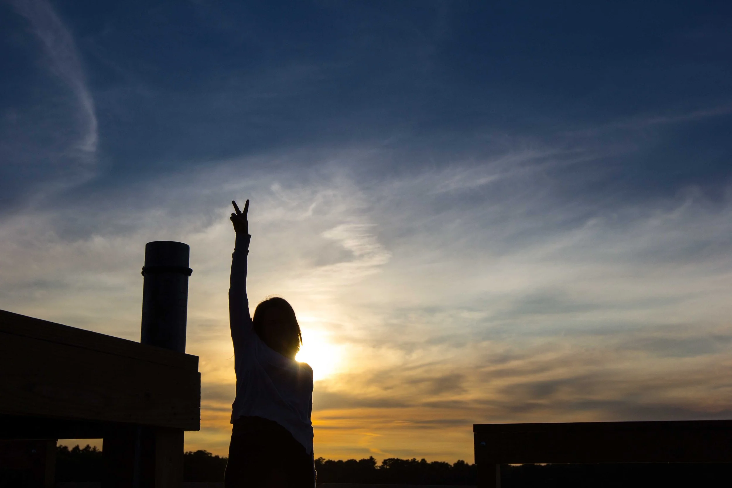 Person silhouetted against sunrise with arms raised in gratitude - morning spiritual practice and sun salutation ritual