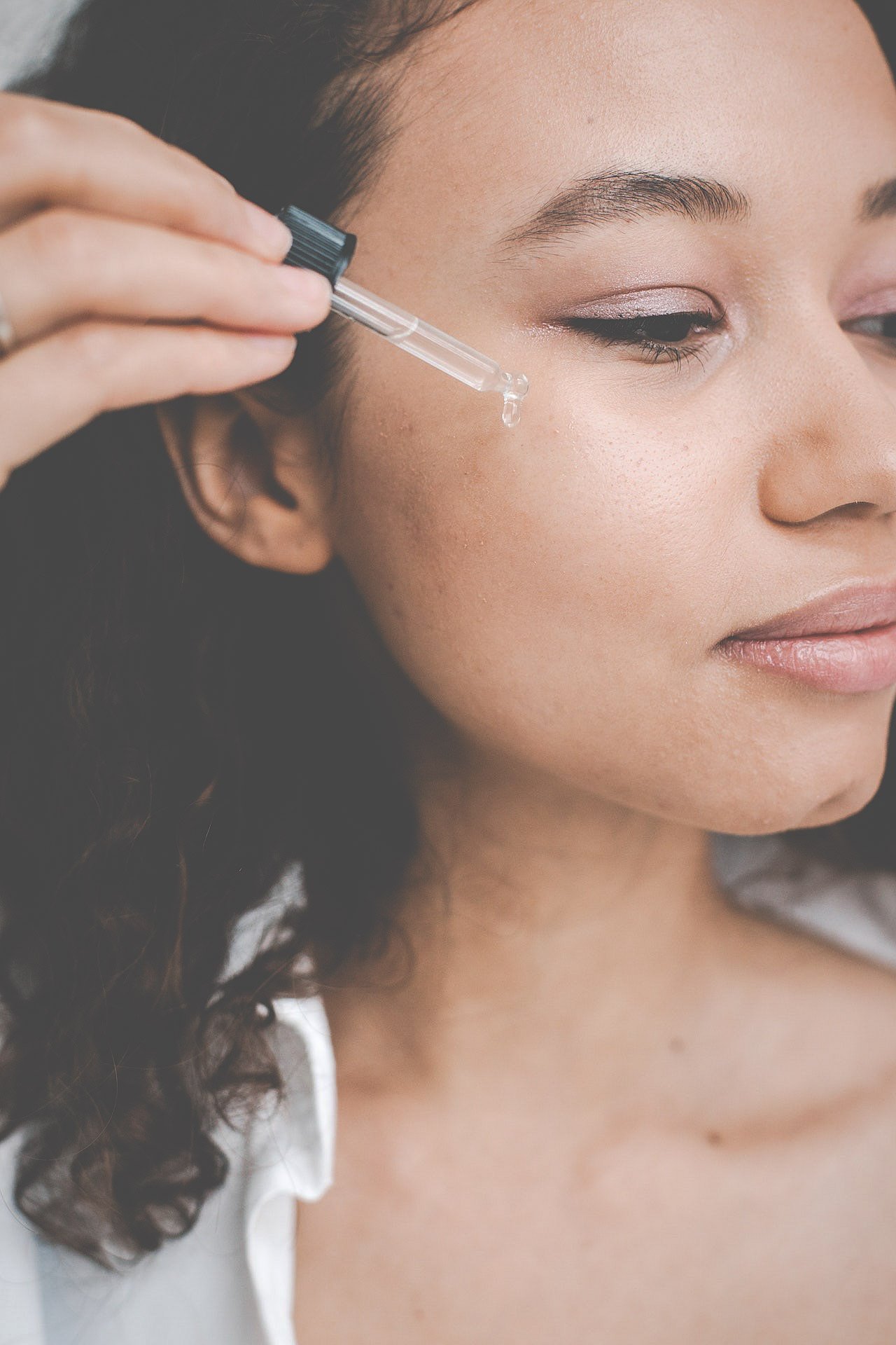 A woman using an eyedropper with Kakadu plum oil from bloom fresh skincare.