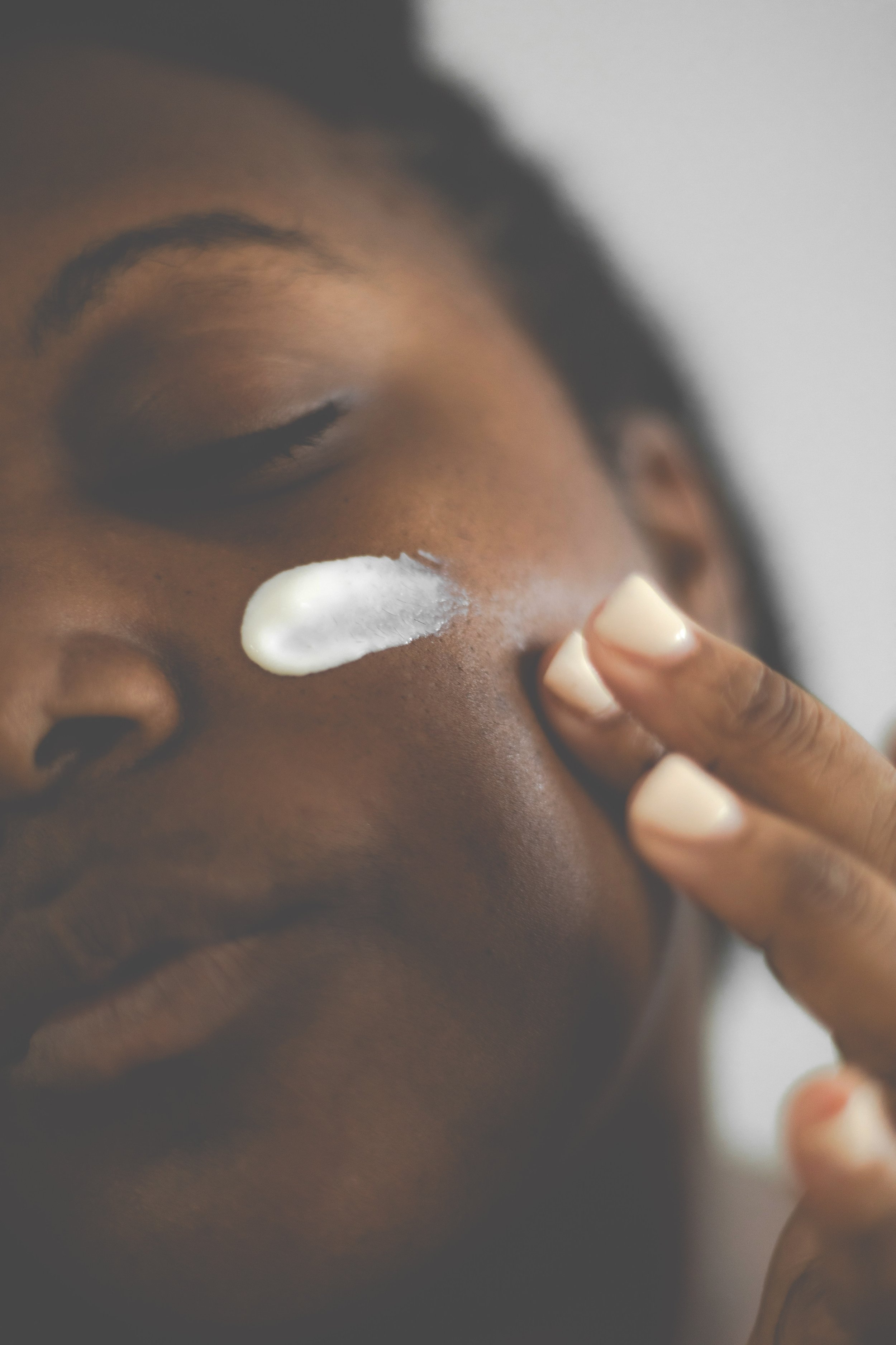 A woman applying radiant renewal facial moisturizer from Bloom Fresh Skincare to her face.