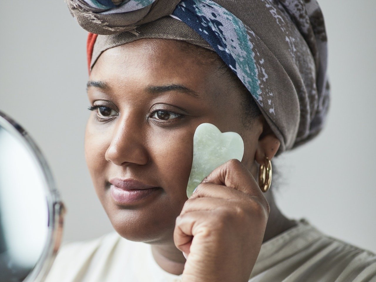 A woman using a jade gua sha around her eye.