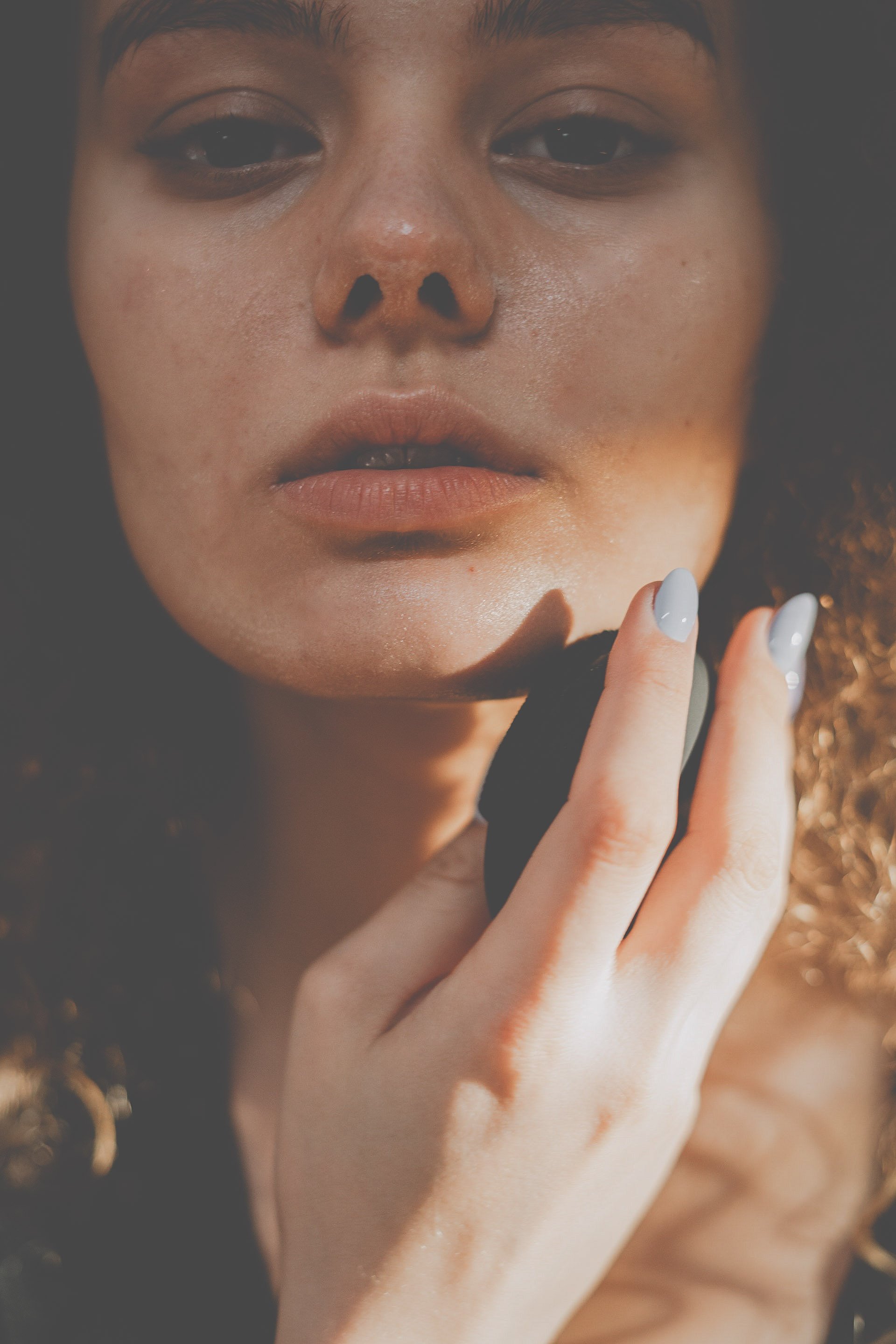 A woman holding a green konjac sponge against her chin.