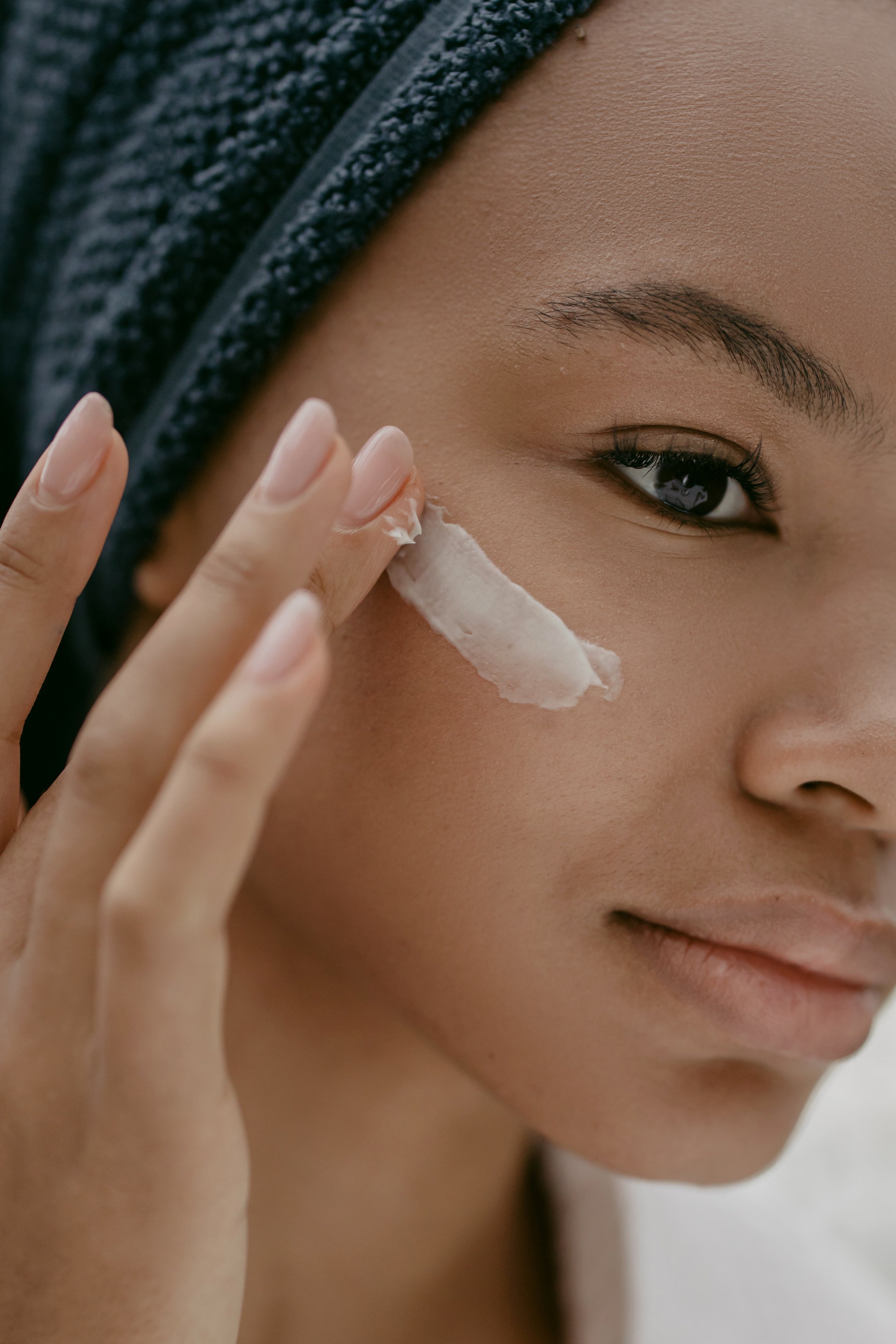 A woman applying a small amount of radiant glow vitamin c serum under her right eye.