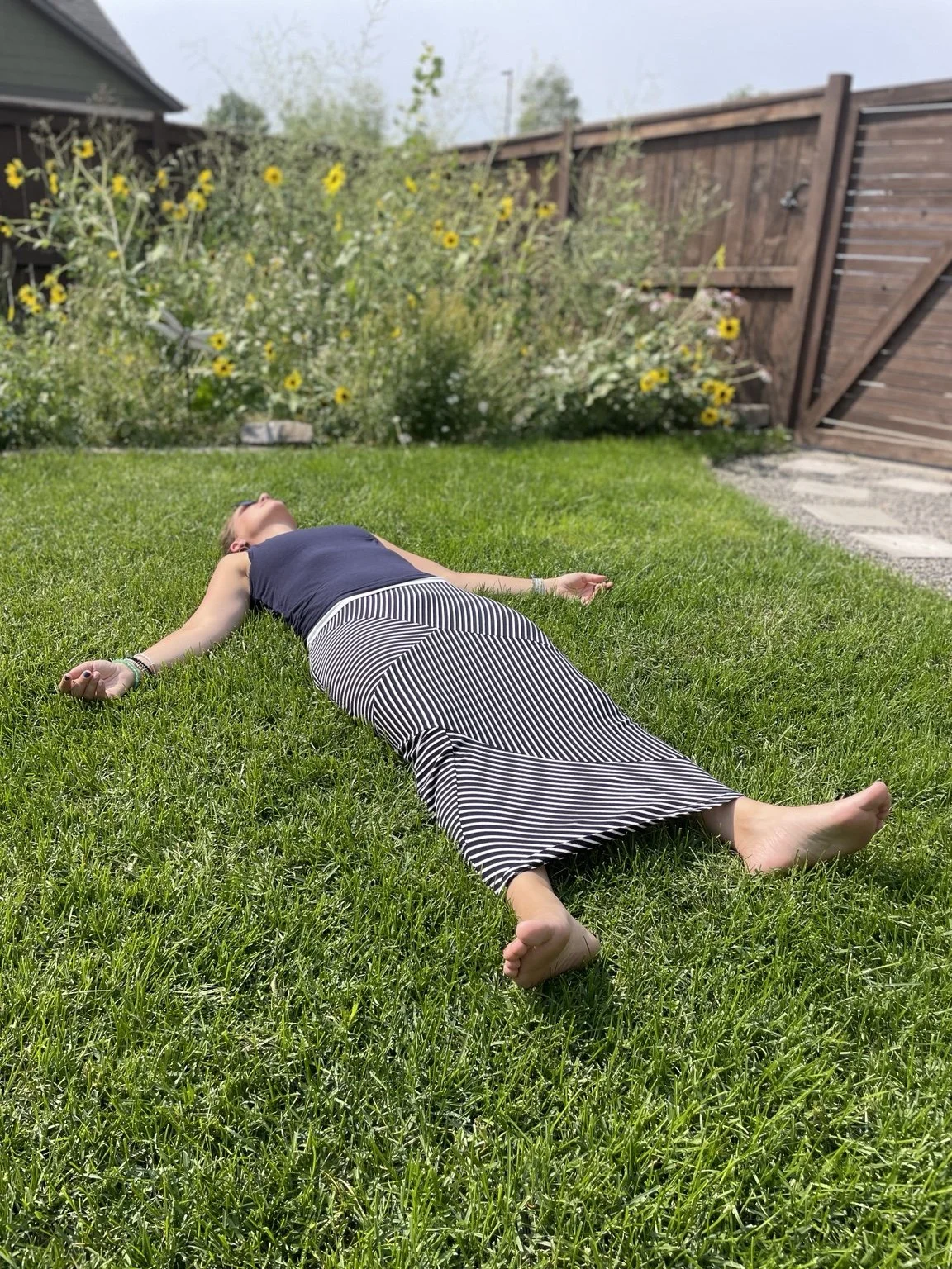Tonia Johnson resting on the grass beneath a tree.