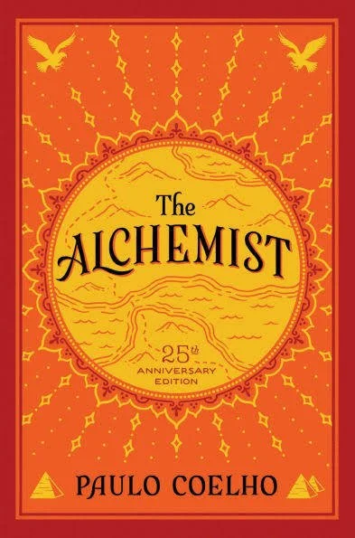 Cover of 'The Alchemist' by Paulo Coelho, 25th anniversary edition, with a yellow circular design and orange background, featuring two birds and decorative patterns.