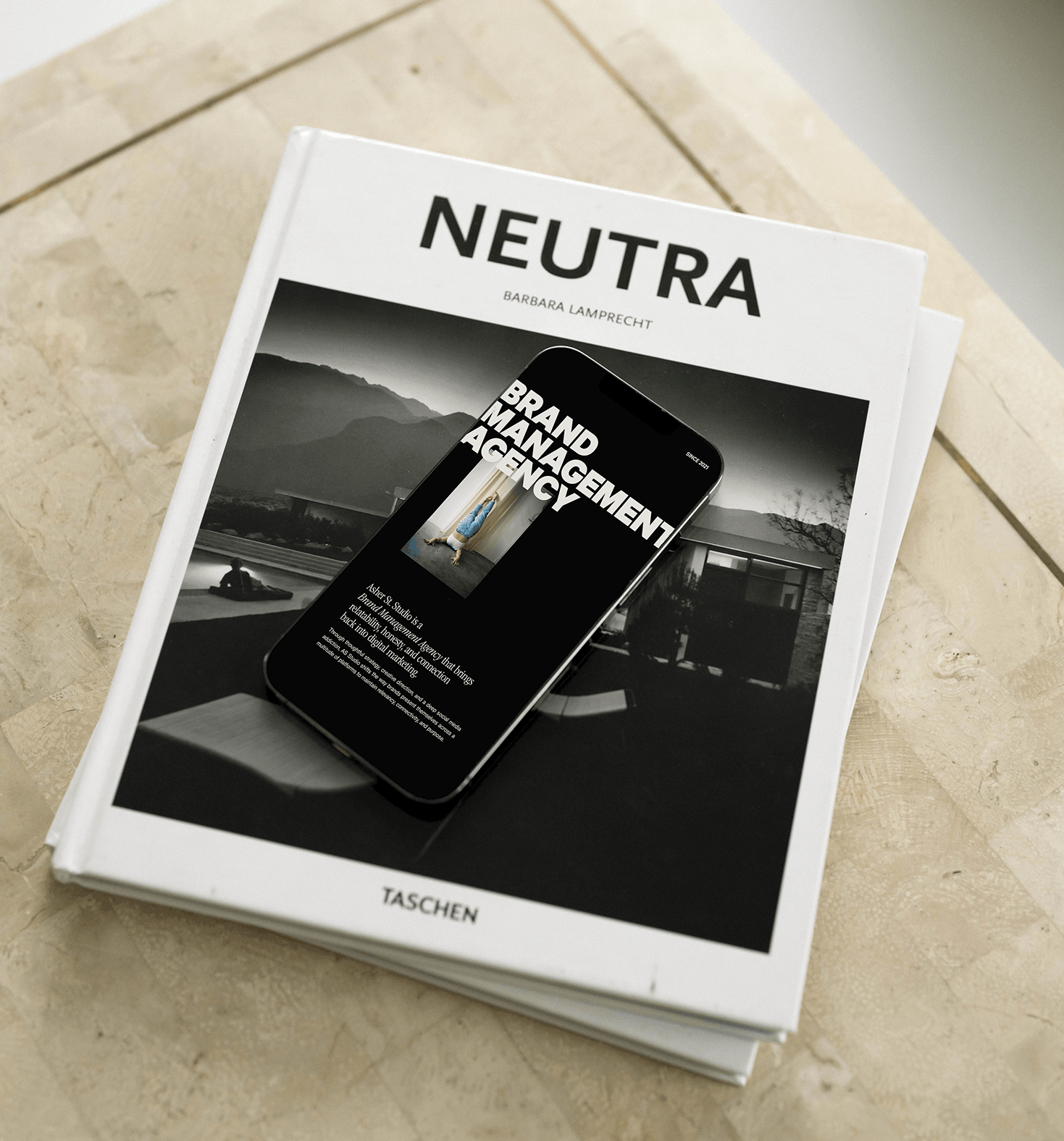 An iPhone sitting on top of a coffee table art book, with website showing Asher St.Studio Brand Management Agency.