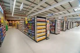 View of grocery store aisles stocked with various products, including canned goods, snacks, and beverages.
