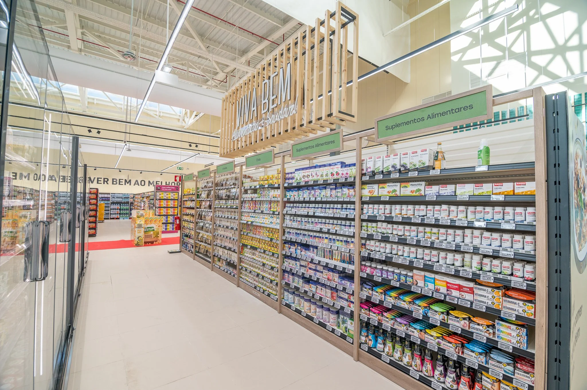Aisle of a pharmacy with shelves filled with various supplements and medications, signage indicating sections for nutritional supplements and vitamins.