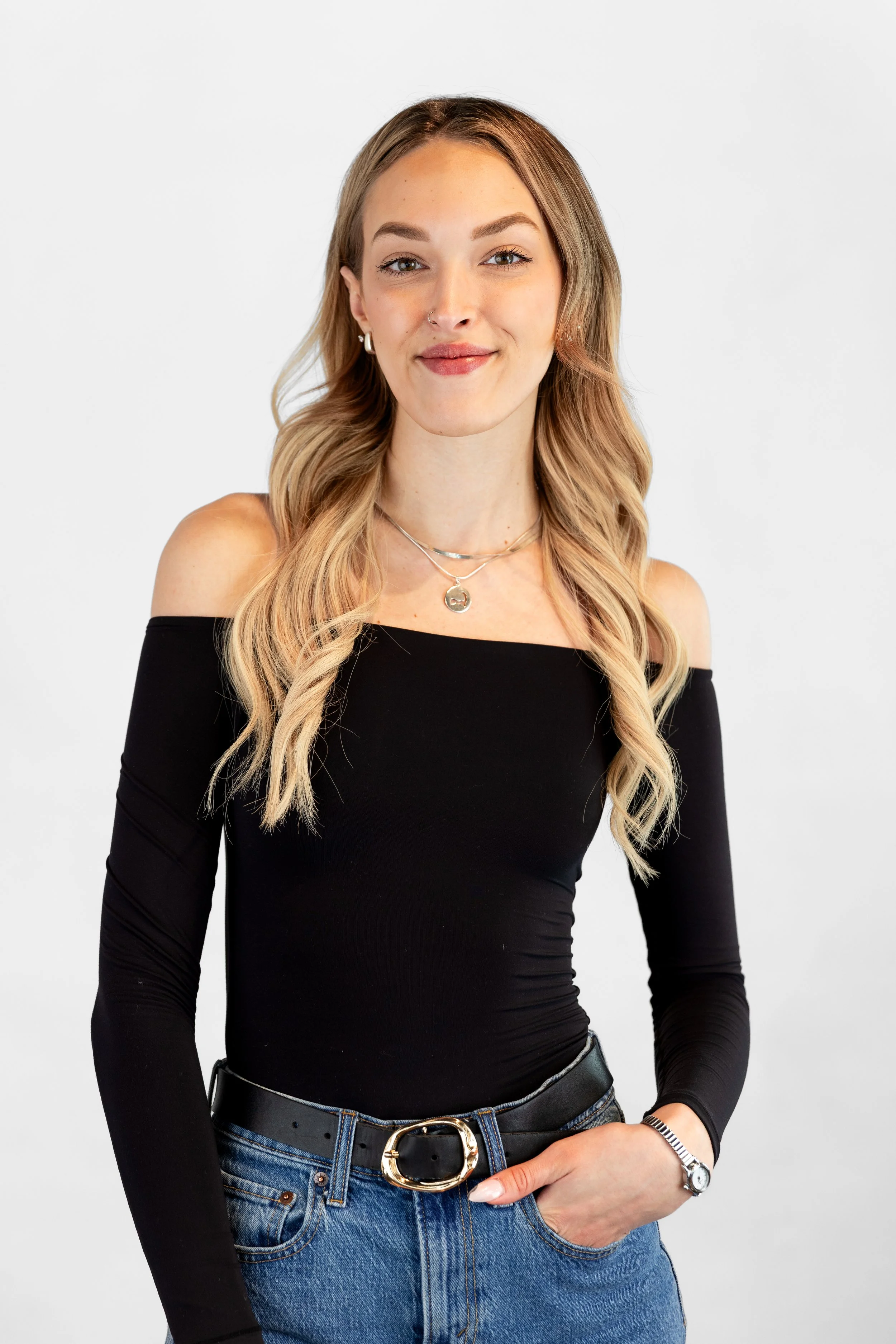 A young woman with long blonde hair sitting on a beige sofa, smiling, in front of a sign that reads 'SOUTH BOSTON' on the wall behind her.