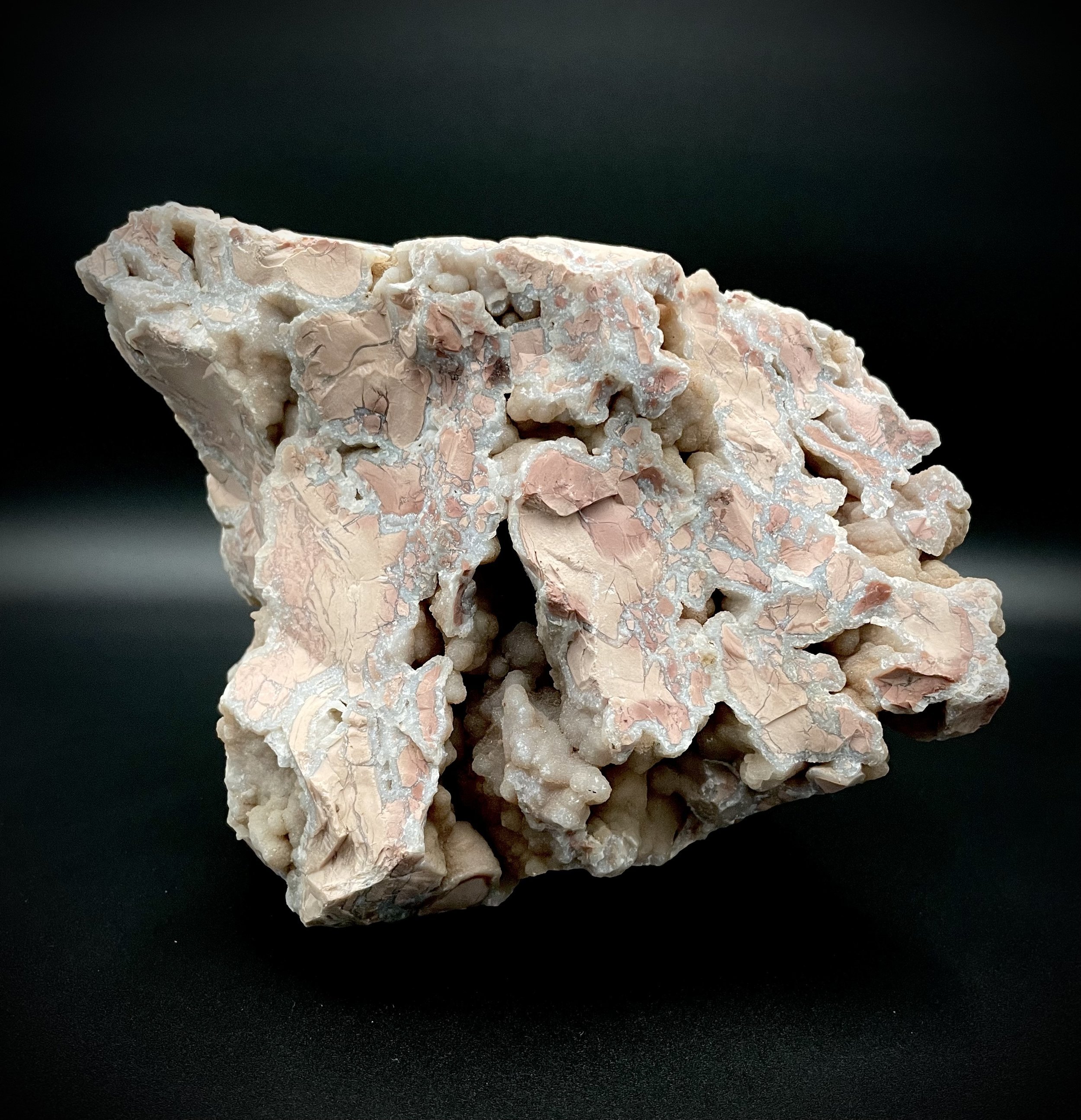 Mounted Wyoming youngite jasper cluster showing pink-tan breccia and UV-reactive agate