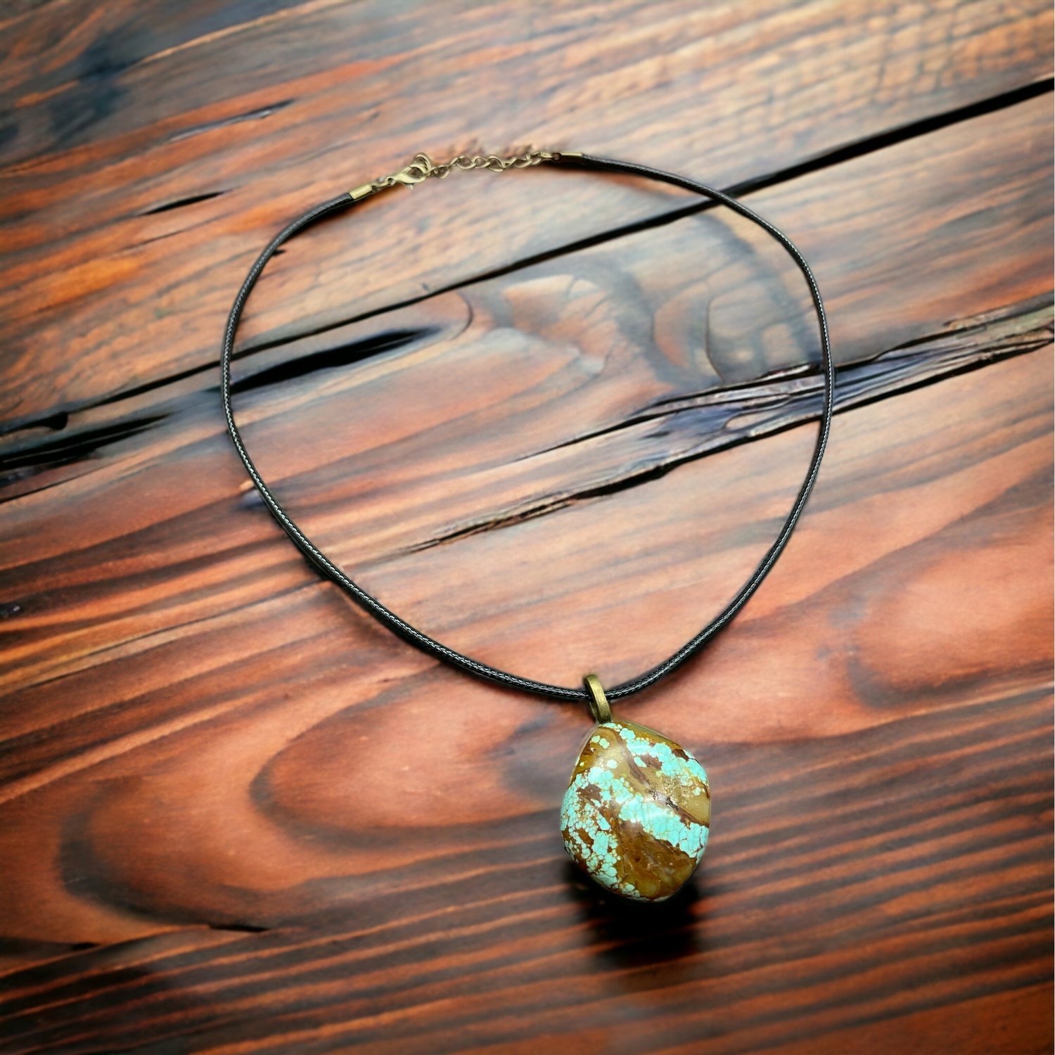 Natural turquoise pendant with blue-green pattern resting on wood surface