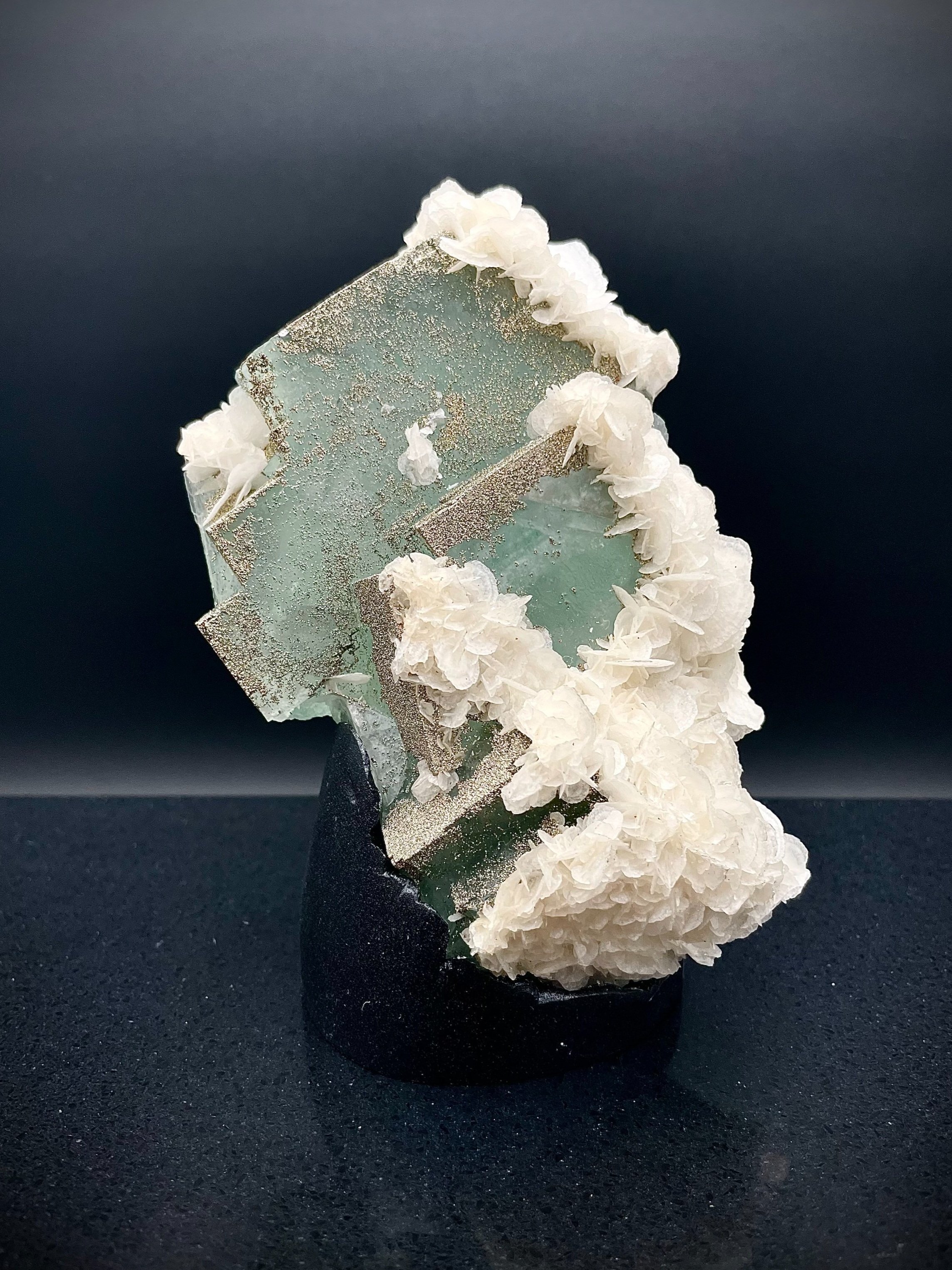 Close-up of calcite flowers and pyrite grains on translucent fluorite
