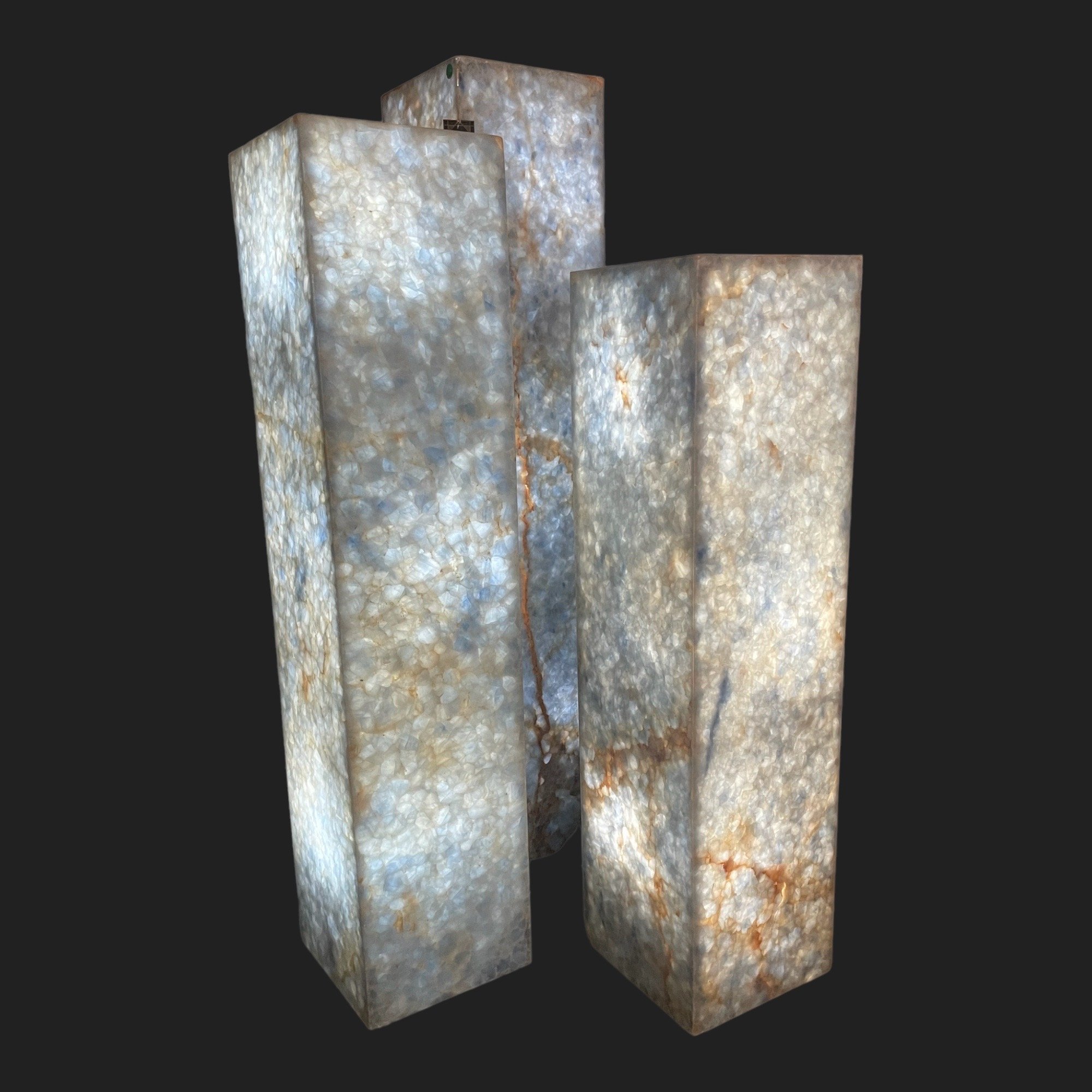 Three translucent calcite tower floor lamps casting soft blue glow