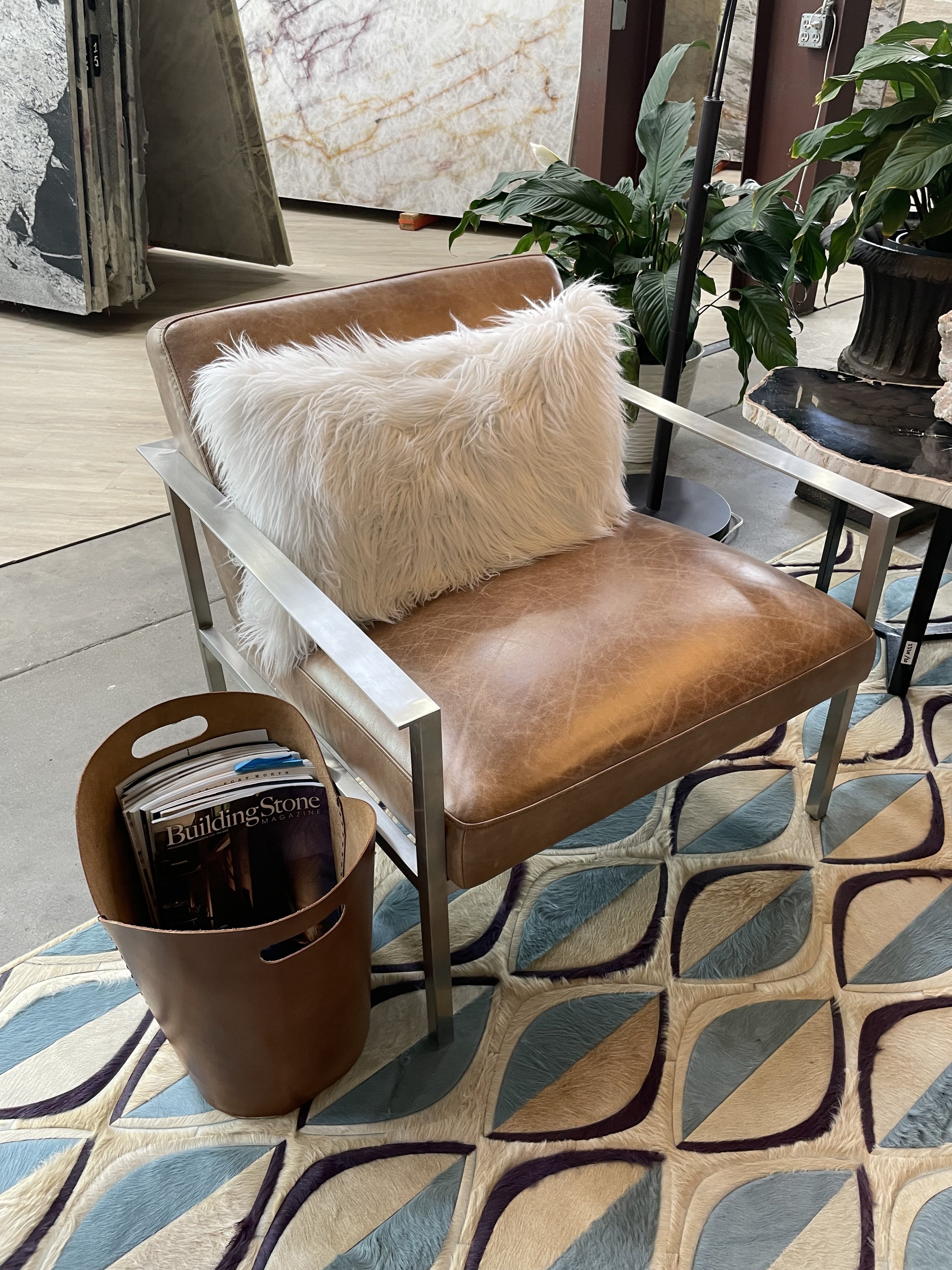 Modern saddle leather lounge chair with stainless steel frame and faux-fur pillow