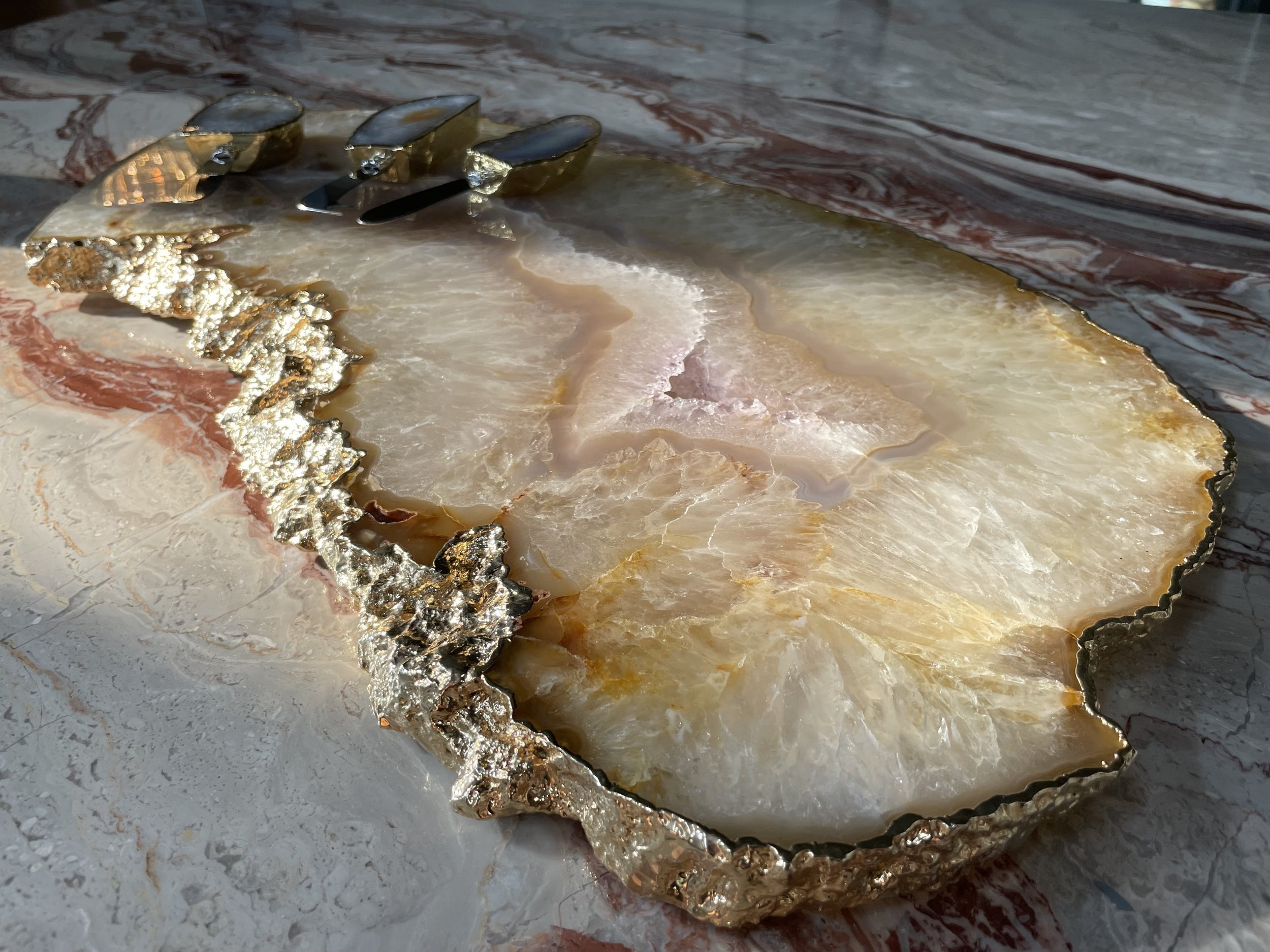 Cheese knife trio with natural agate handles resting on luxury stone cheeseboard