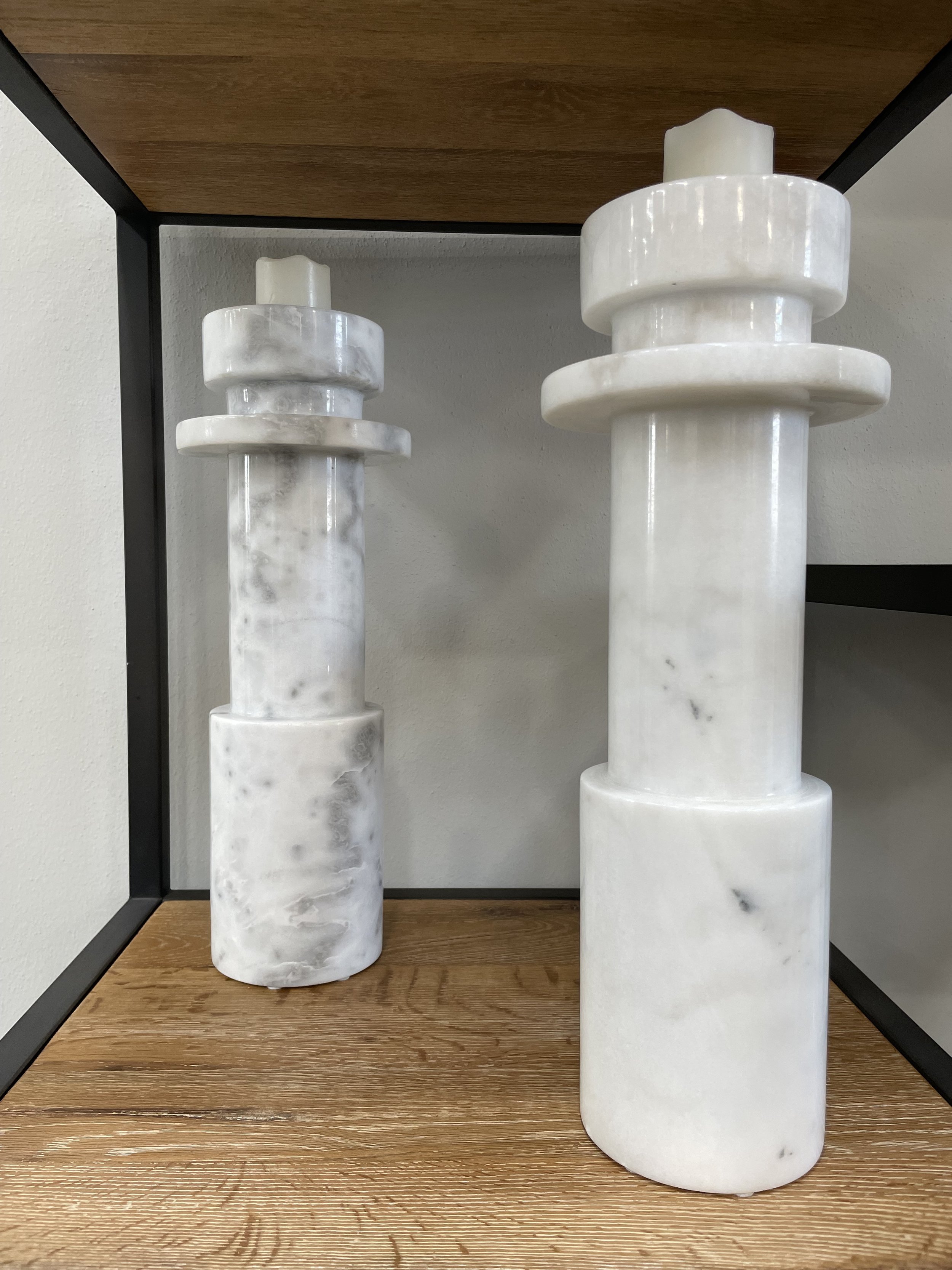 Pair of tall white marble pillar candle holders on wood coffee table in Dallas living room
