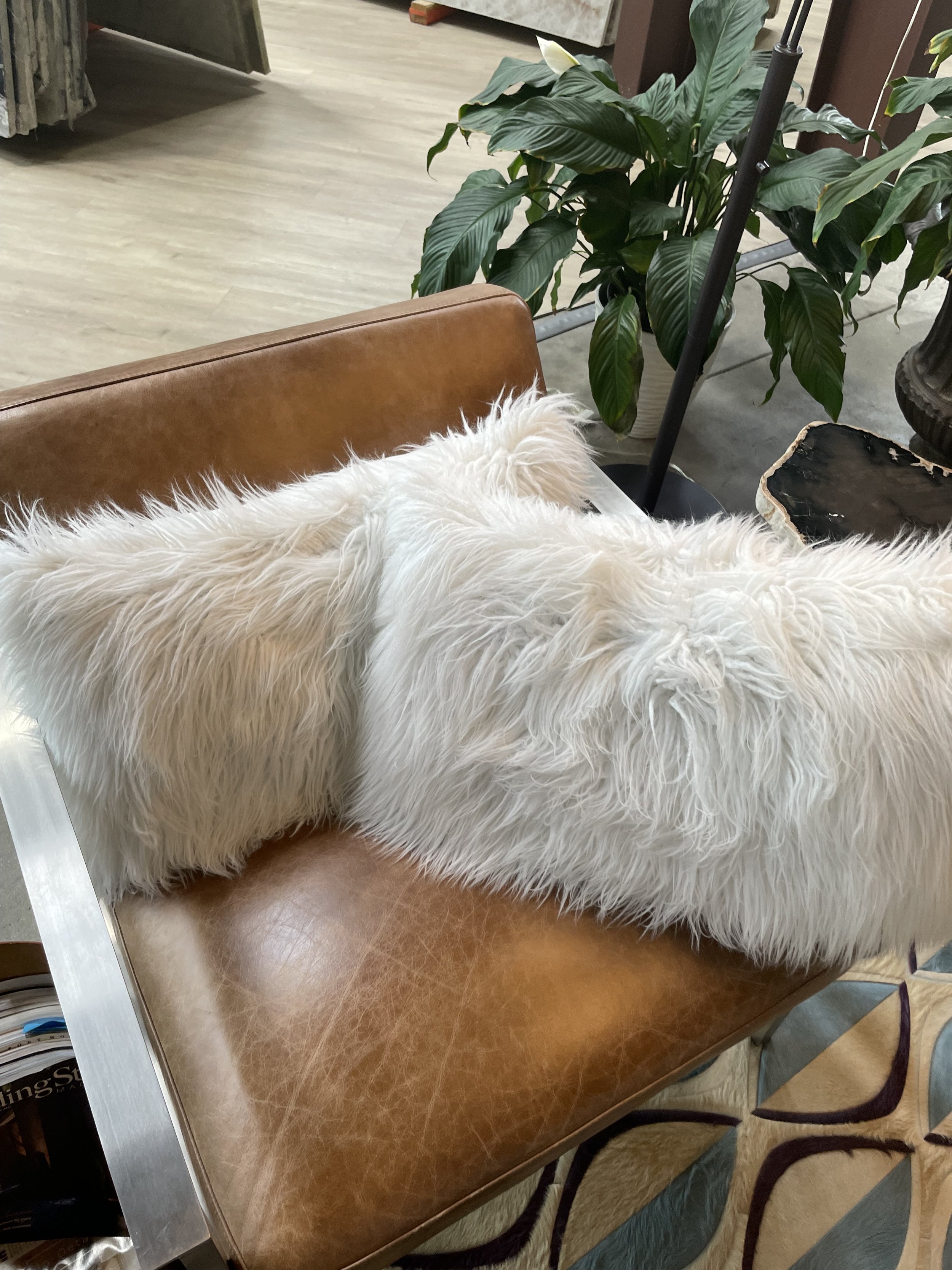 Modern saddle leather lounge chair with stainless steel frame and faux-fur pillow