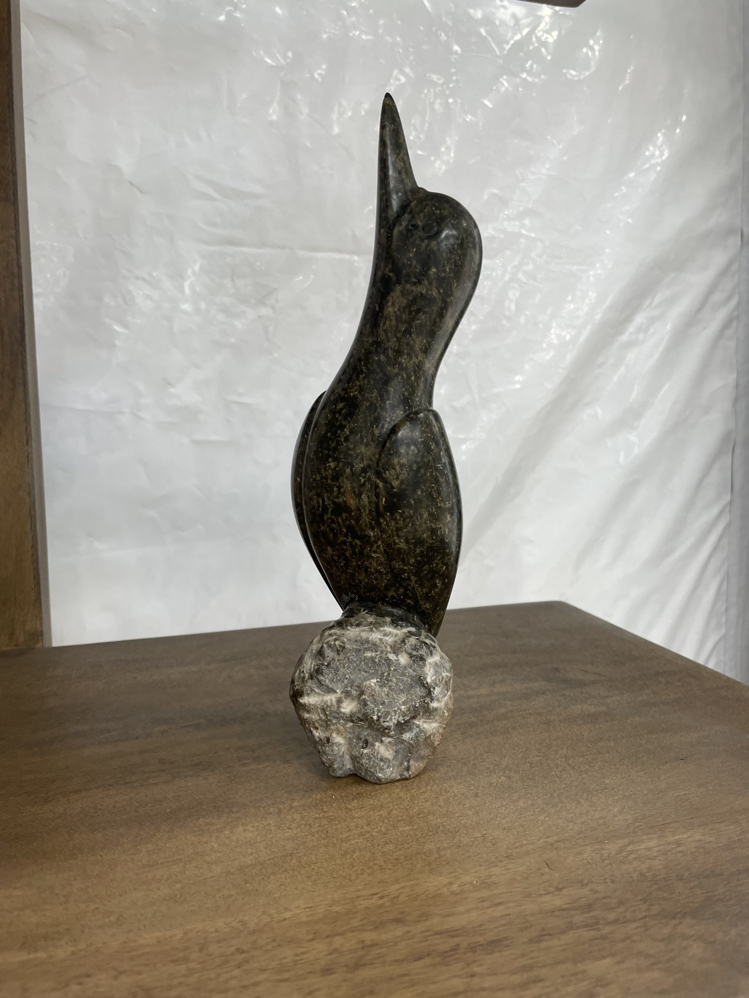 Hand-carved dark serpentine cardinal sculpture on natural stone base