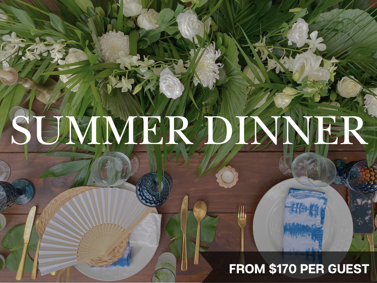 Elegant outdoor summer dinner setup with a long wooden table, floral centerpieces, candle holders, wine glasses, and chairs, bathed in natural light.