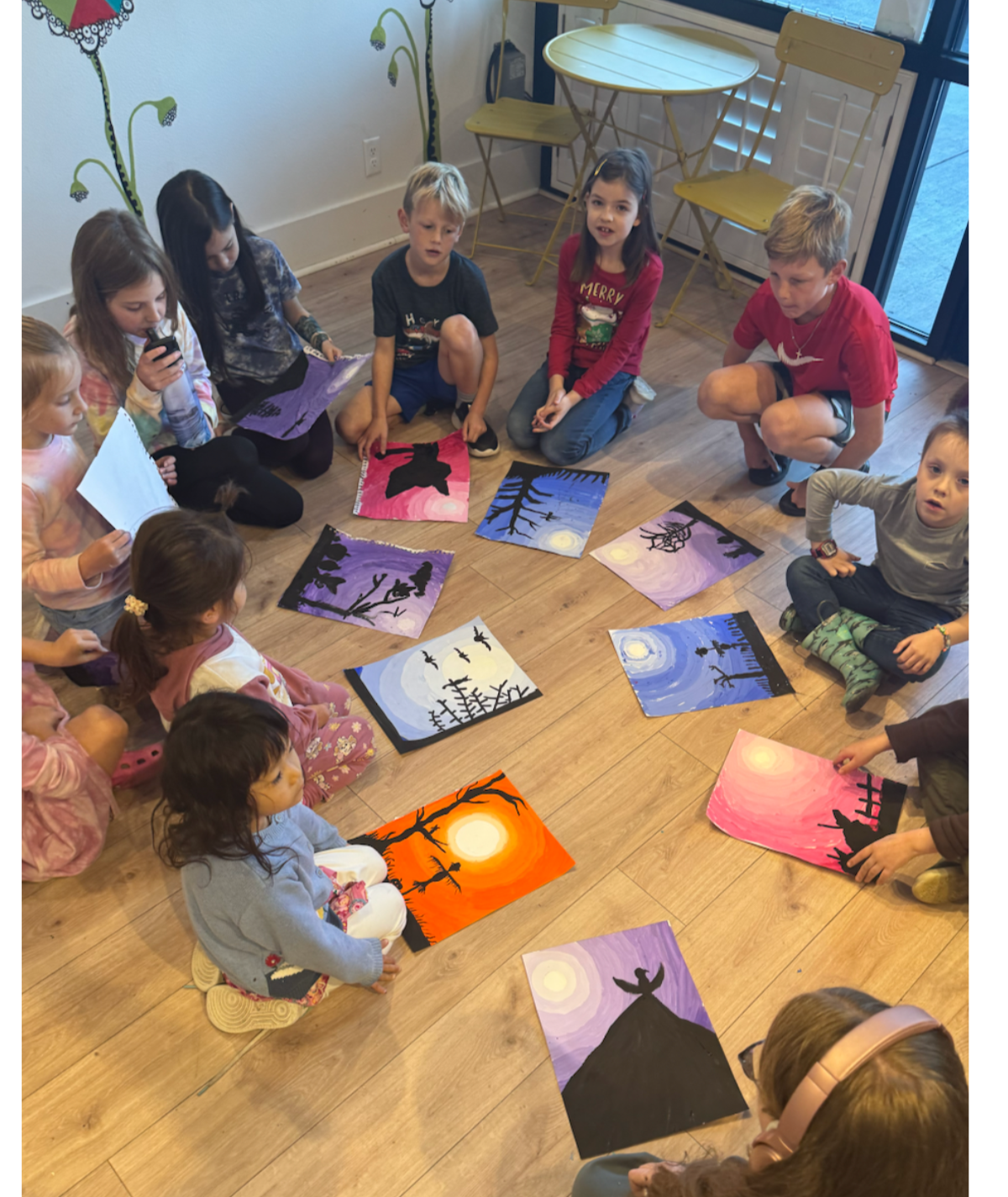 Kids sitting in a art circle talking about their colorful artwork during an after-school art class at Whimsy Wees Art Studio in Beaverton, Oregon