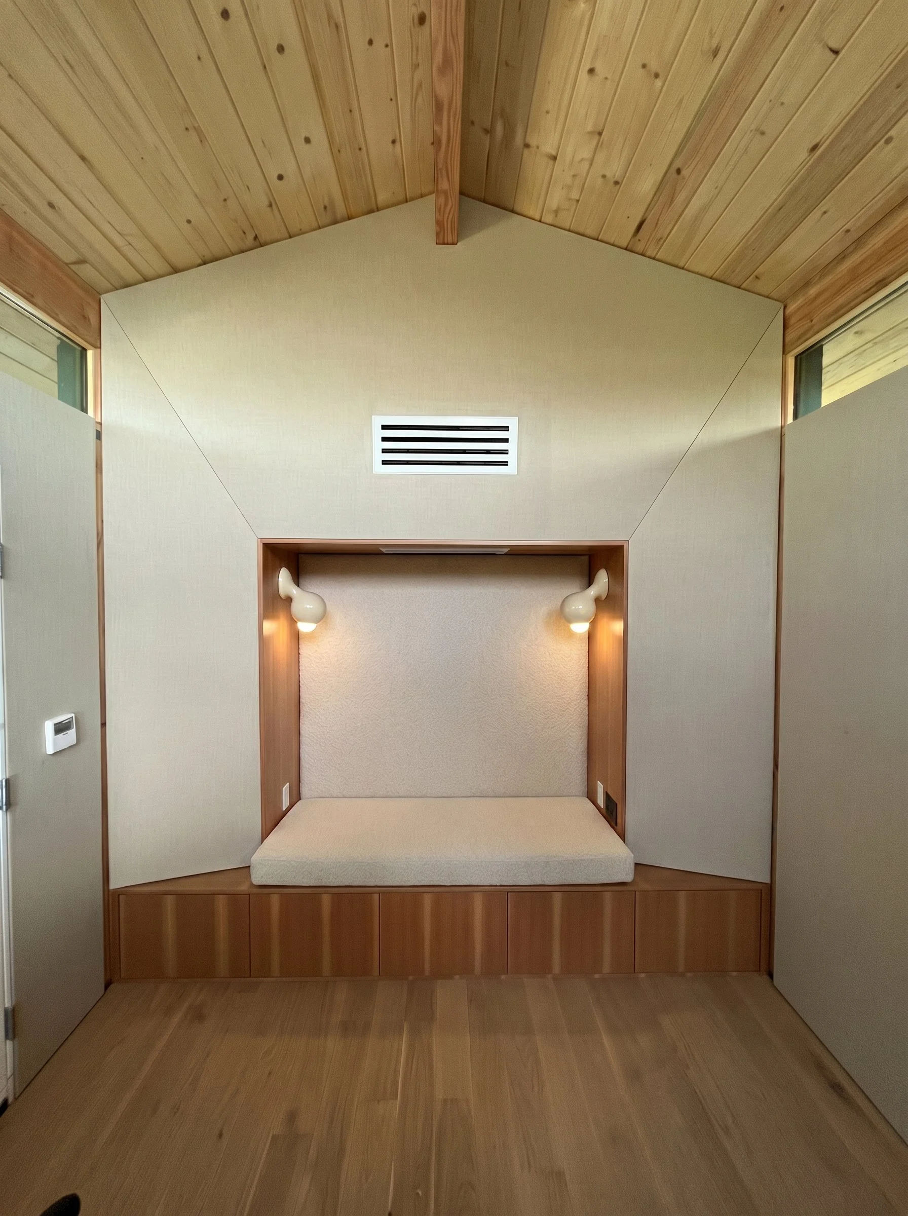Concealed behind fabric-wrapped surfaces, a 24-inch-deep bass trap provides acoustic control while built-in seating and Douglas fir storage create a warm, residential atmosphere.