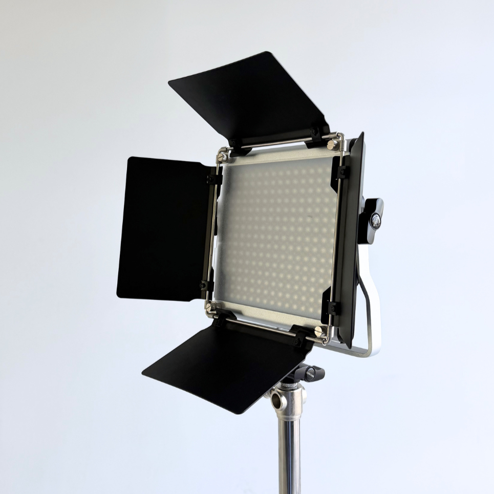 A professional LED studio light with barn doors, mounted on a metal stand, against a plain white background.