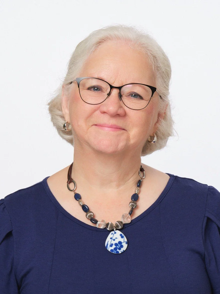 Elderly woman with glasses smiling against a blue background