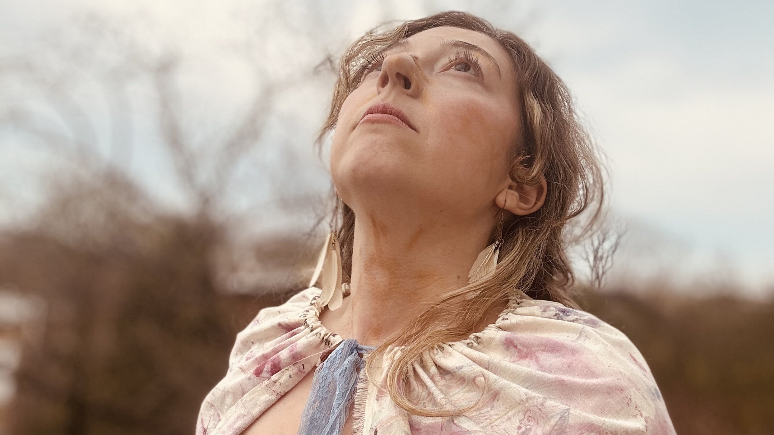 multidisciplinary artist Nicole Javorsky looking up to the sky while wearing a cape she created