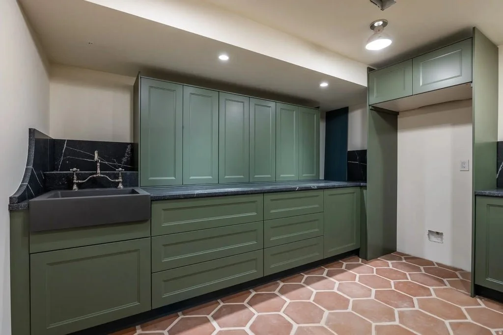 Kitchen with green cabinetry, black countertops, black farmhouse sink, black backsplash, terracotta hexagonal tile flooring, recessed ceiling lights, and a wall closet.