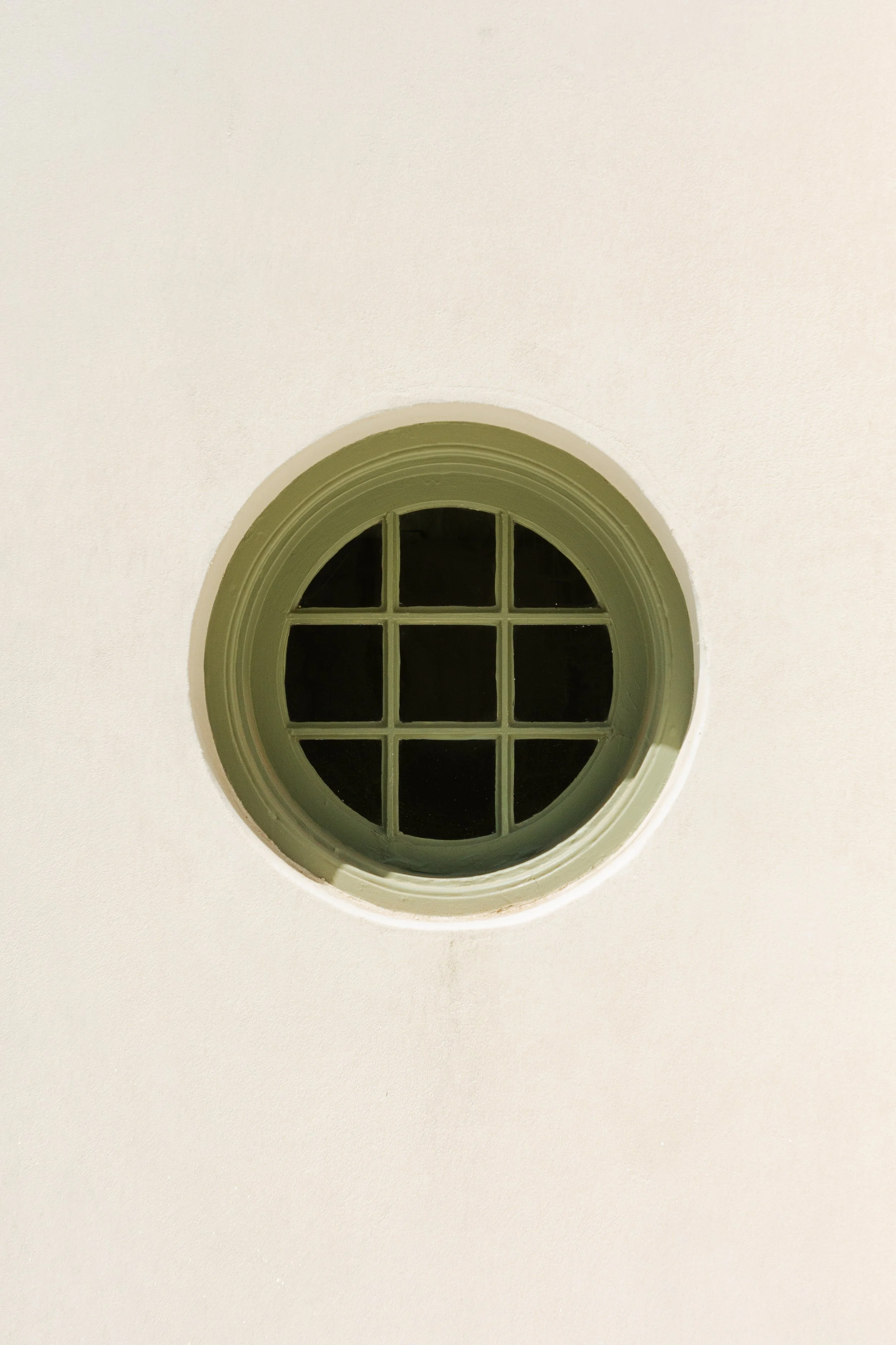 Circular window with multiple panes on a plain white wall.