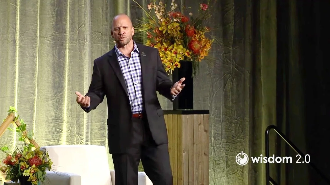 Dan Nevins giving a speech on stage.