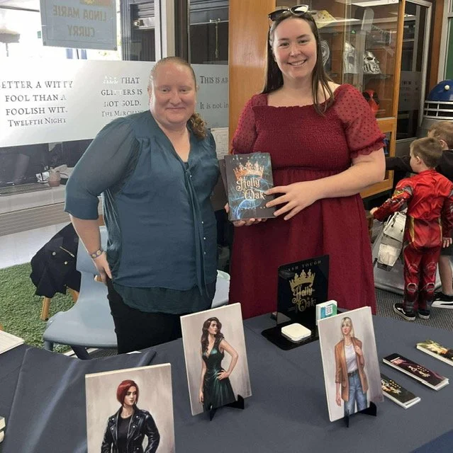 A book titled 'Holly and Oak' by Ash Trough resting on a wicker table by an outdoor swimming pool. The pool has a few people swimming, with a sign for Tirita Pool Bar in the background.
