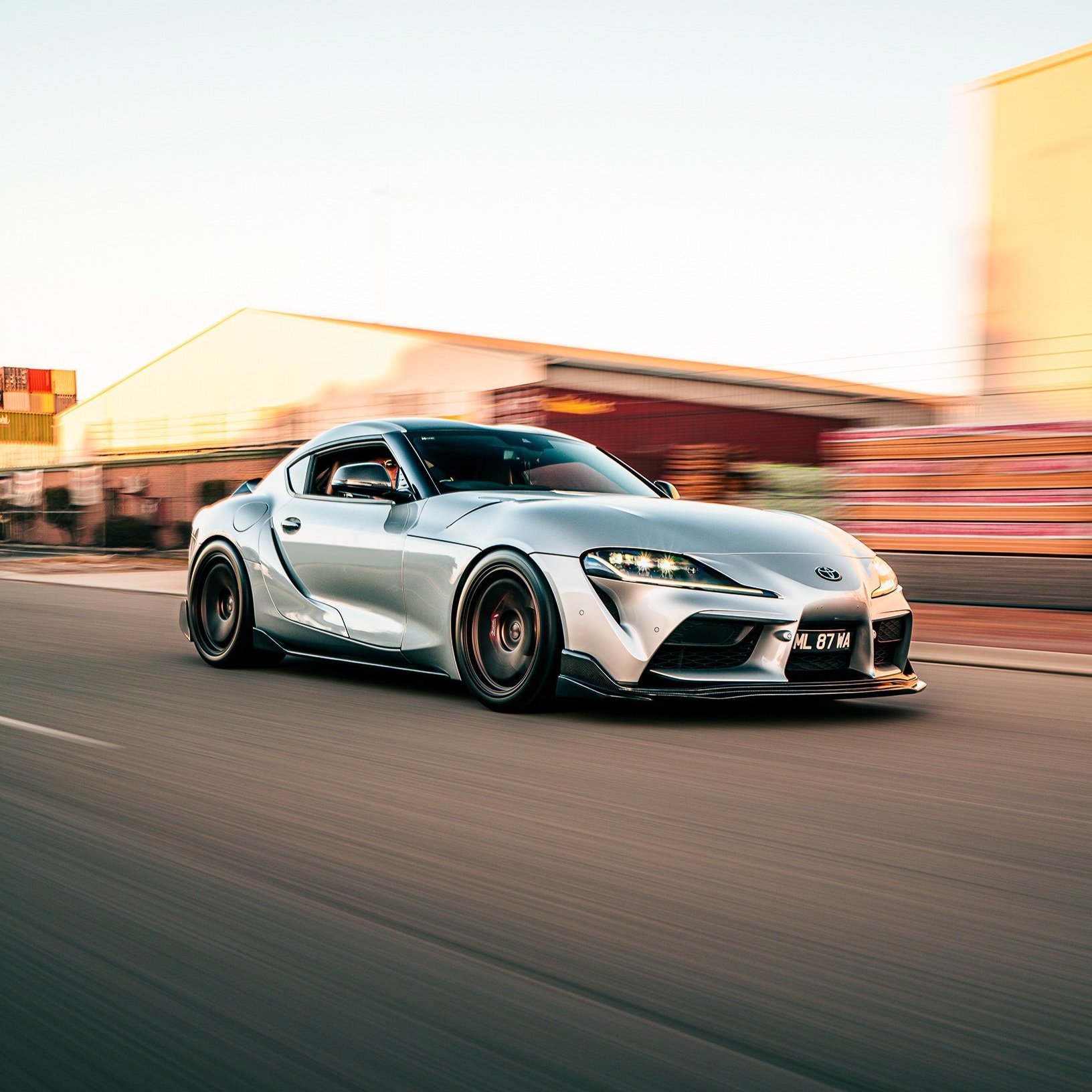 Silver sports car driving fast on urban road with motion blur background.