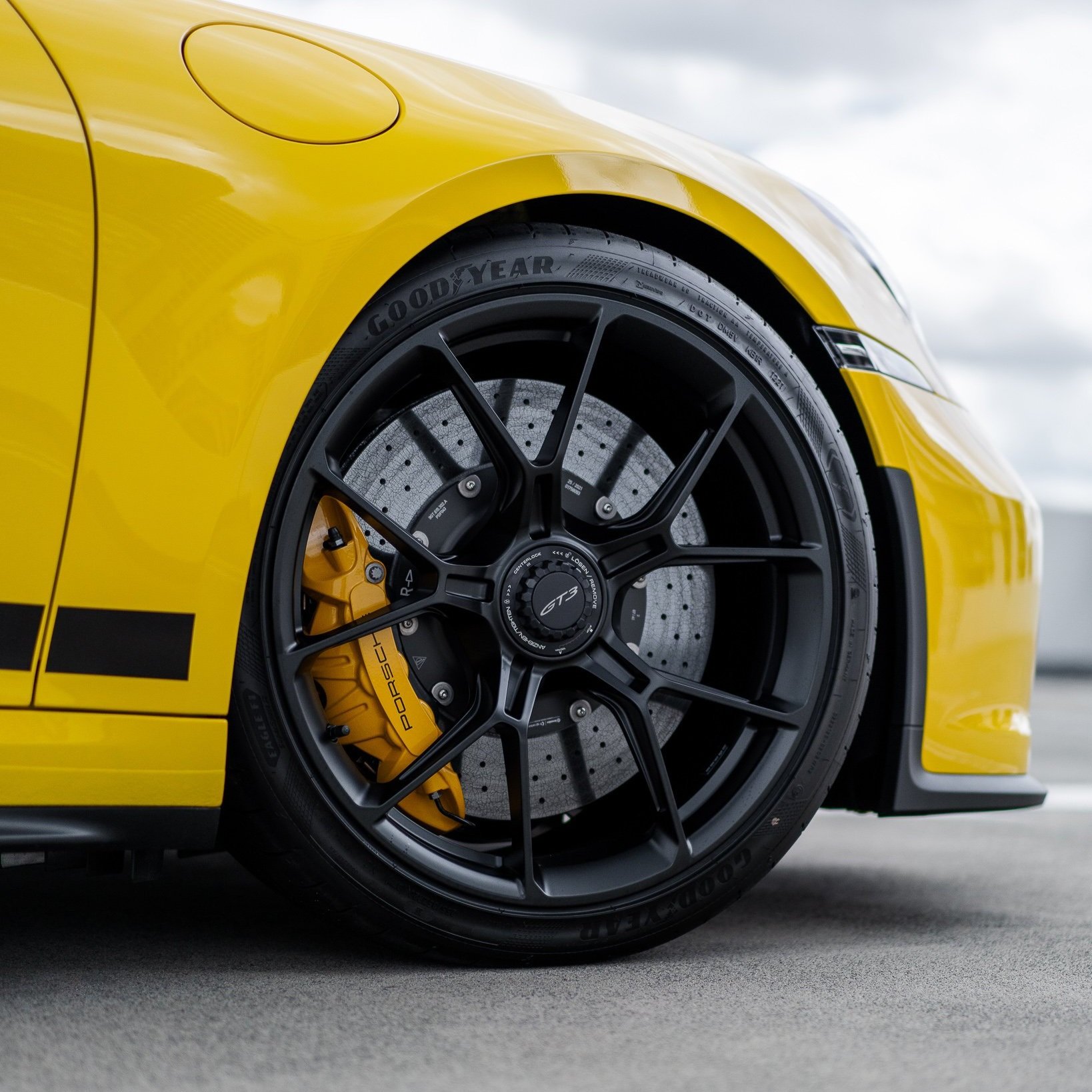 Close-up of yellow sports car wheel with black alloy rim and Goodyear tire.