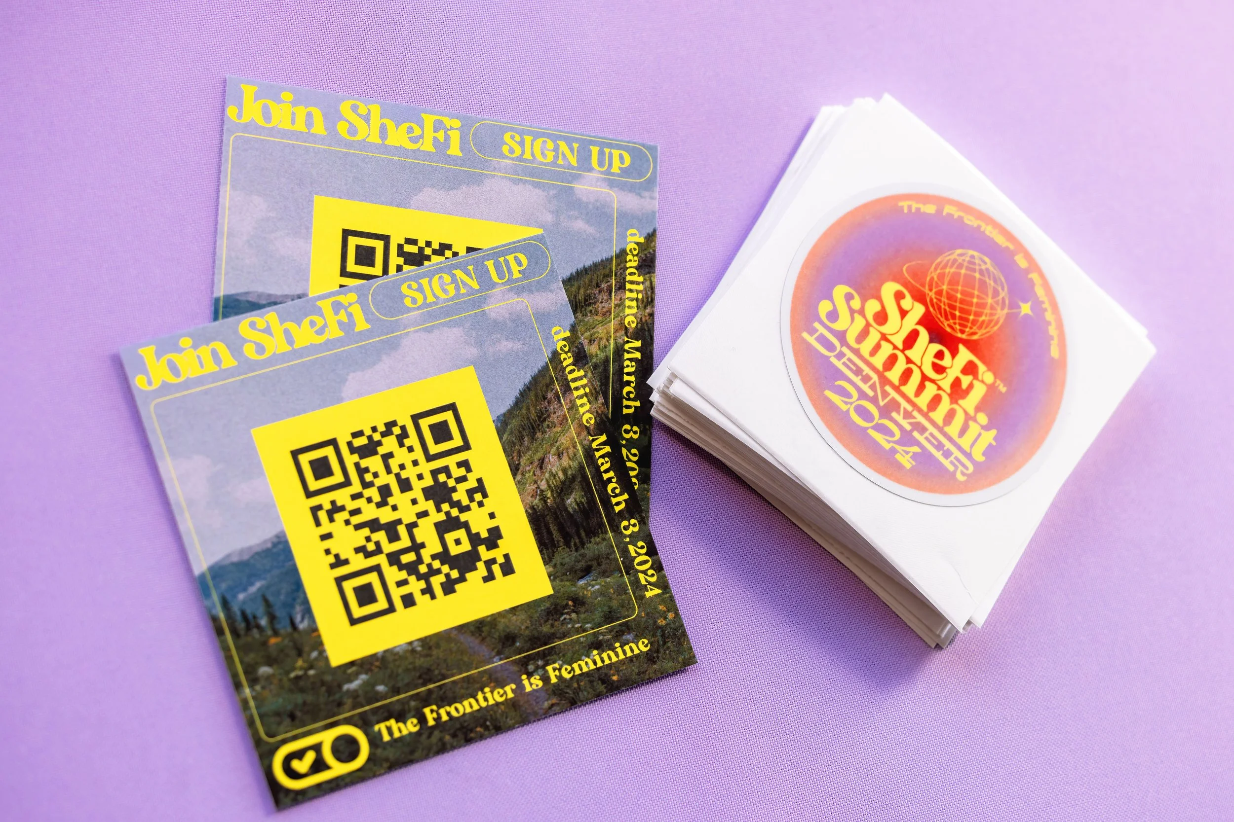 Flyers for "Join SheFi" with a QR code and "SheFi Summit Denver 2024" stickers on a purple background.