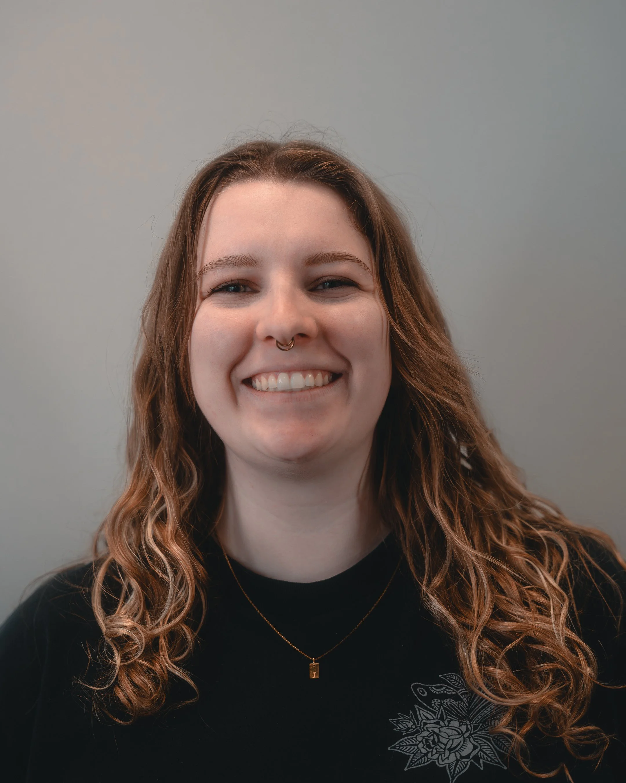 Person with tattoos and blonde hair wearing a black hoodie.