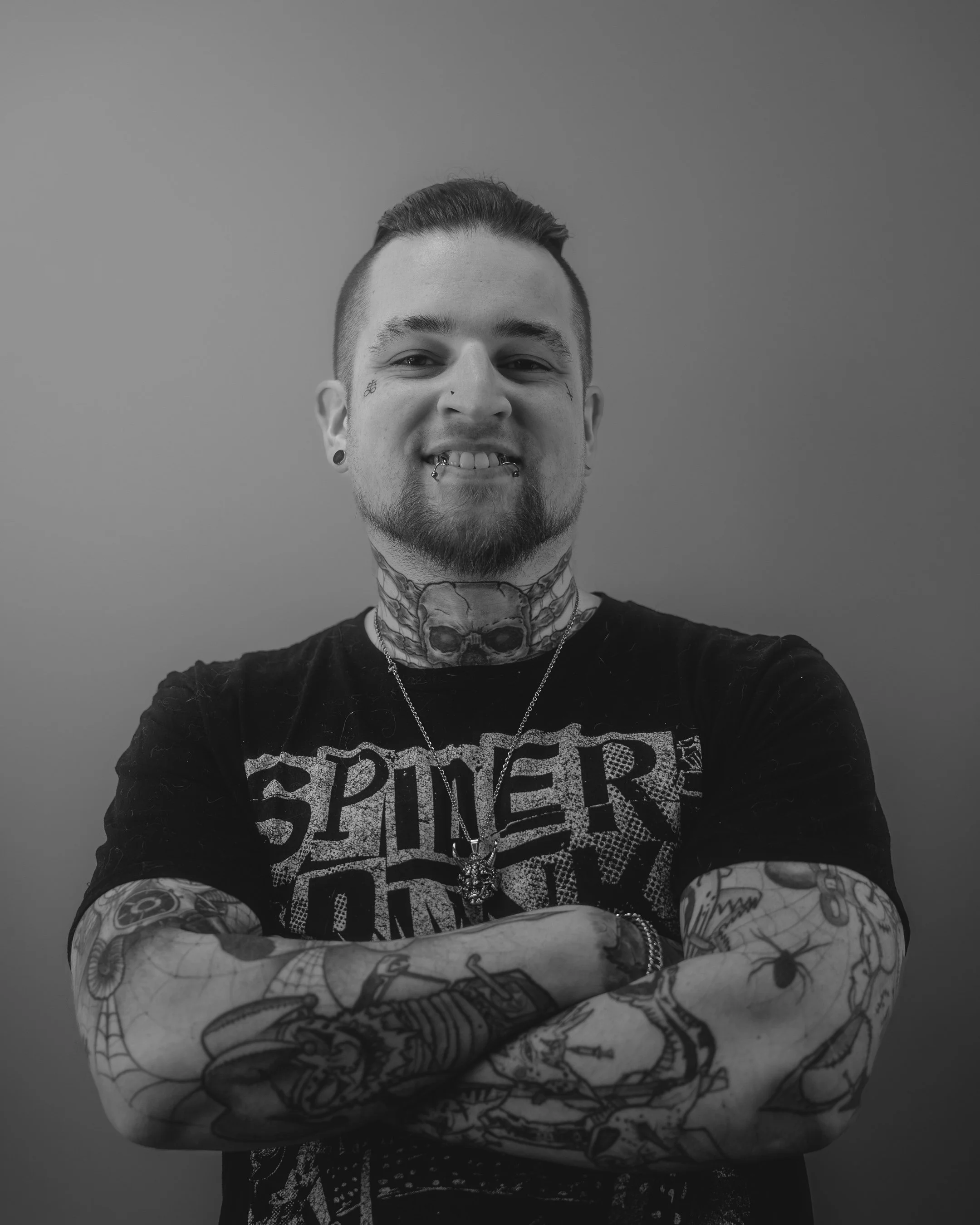 Person with glasses, beanie, and tattoos