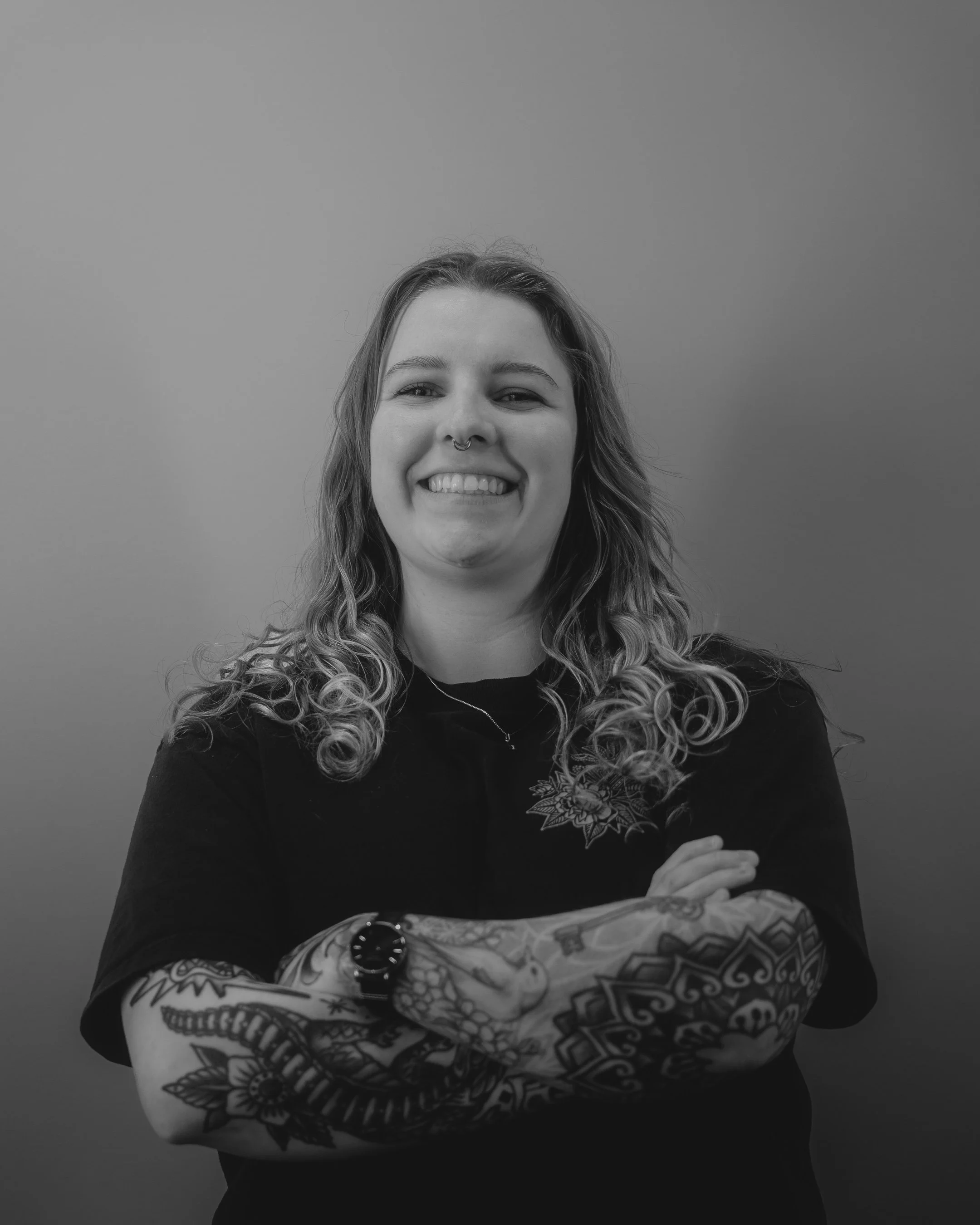 Person with tattoos and blonde hair wearing a black hoodie.